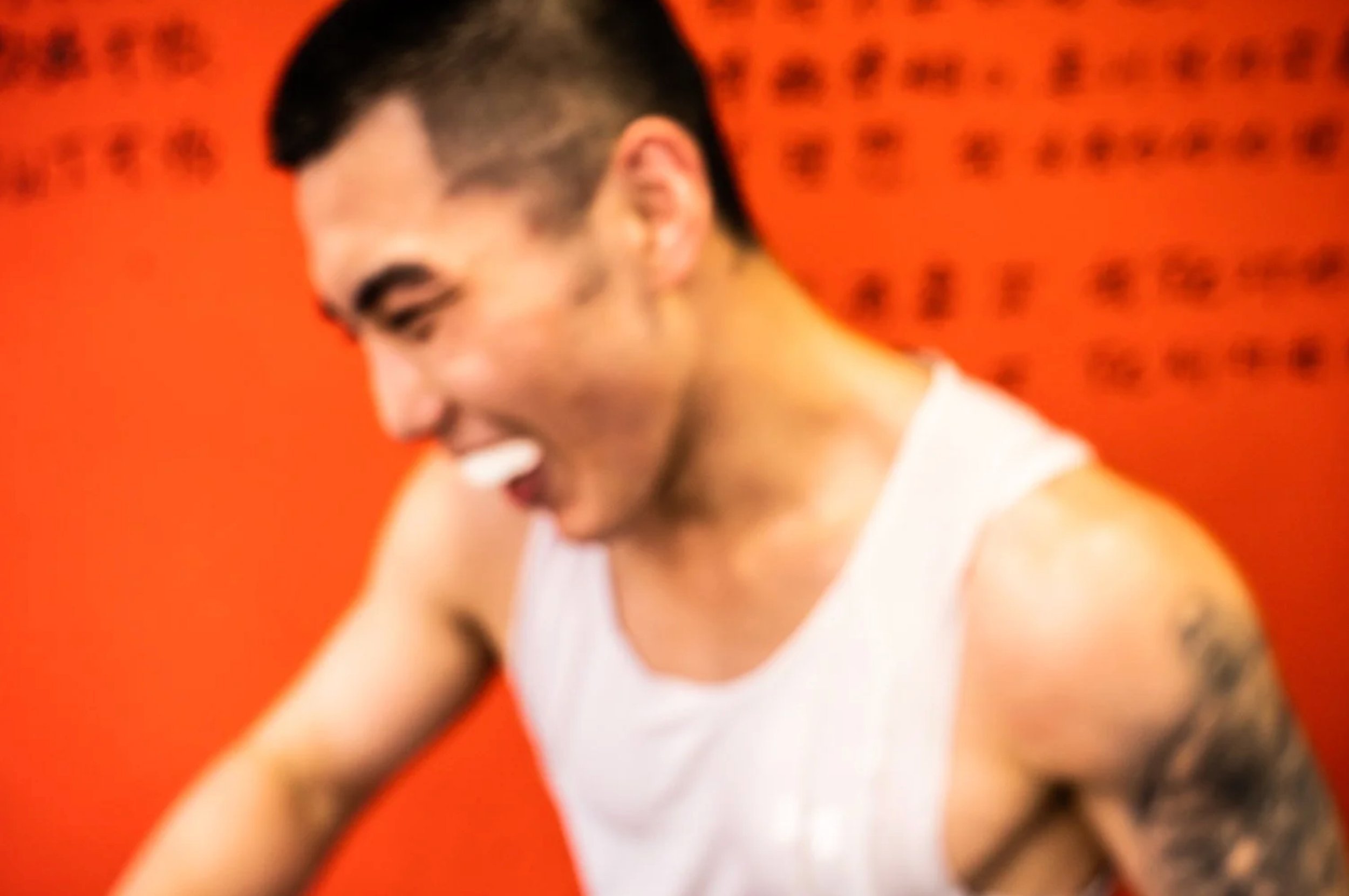 Laughing man in a white tank top against a red wall — Shanghai fashion and portrait photography | Victor Marvillet photographer
