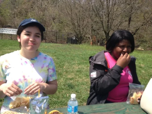 Claire and A'Lexus picnic on their lunch break at the National Arboretum during a City Kids canoe trip