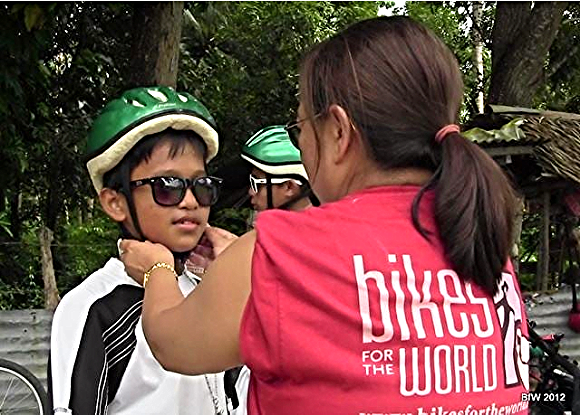 In the Philippines, a BfW volunteer fits a child with a helmet./Photo courtesy of Bikes for the World