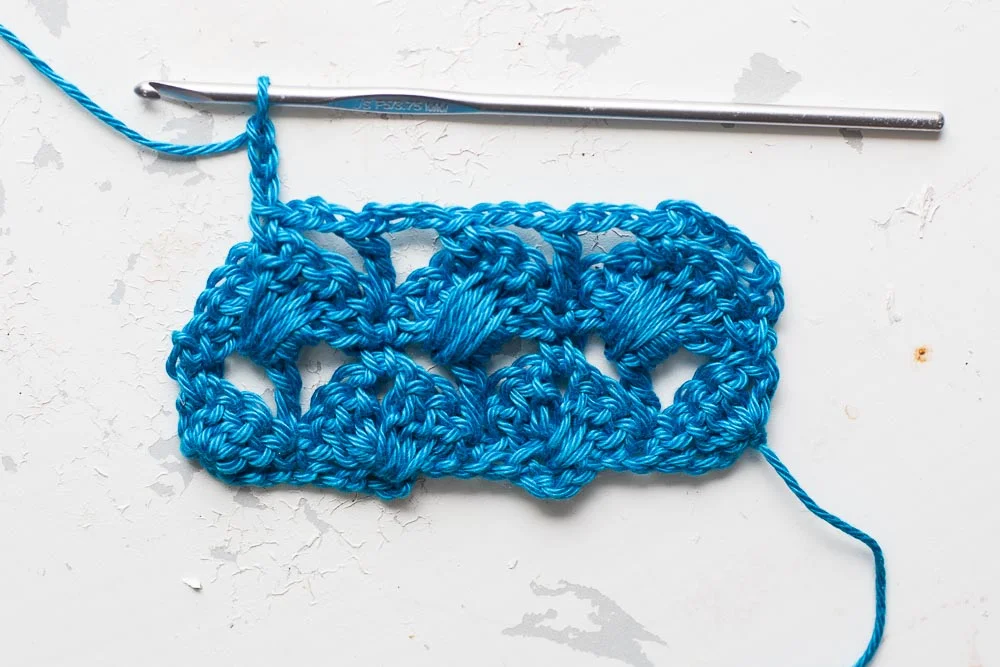 Step 3: Continue working this bridging pattern across, with dcs into the top of the shell stitches and trebles into the dcs in the row below, with 3 chain spaces bridging the gaps between the stitches. 