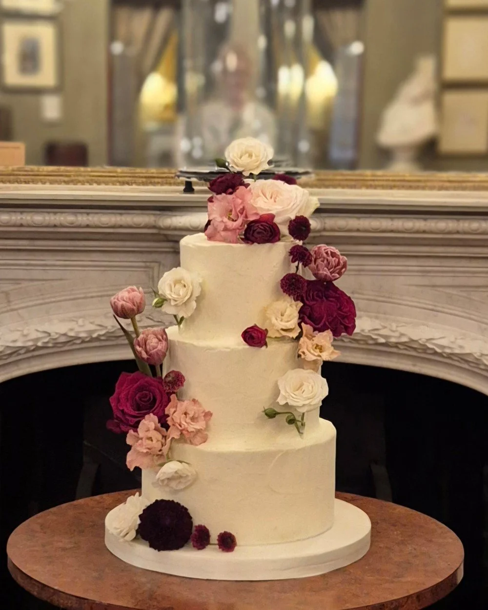 buttercream wedding cake with fresh flowers in red and pink