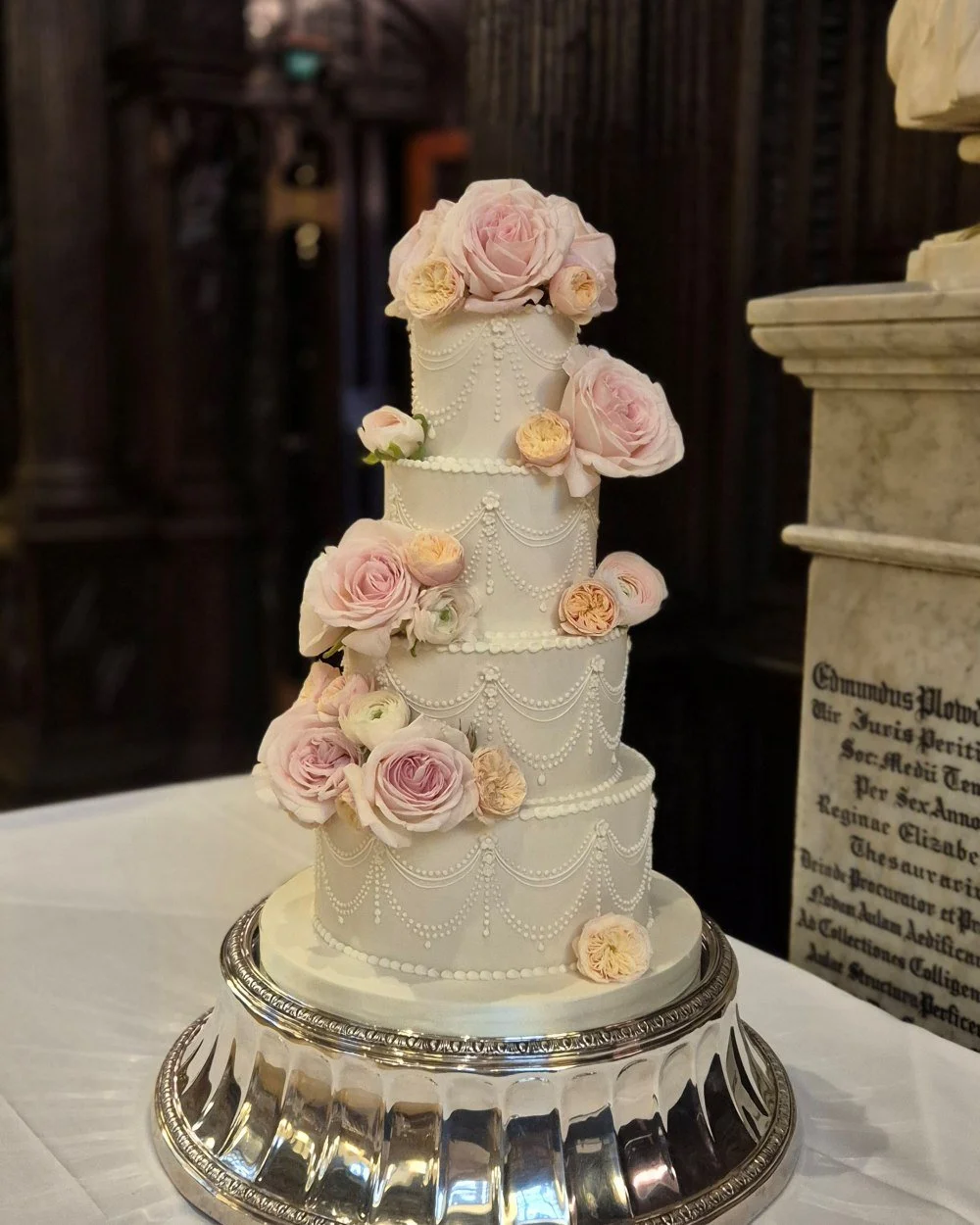 A traditional wedding cake with delicate piping and fresh flowers in middle temple hall London