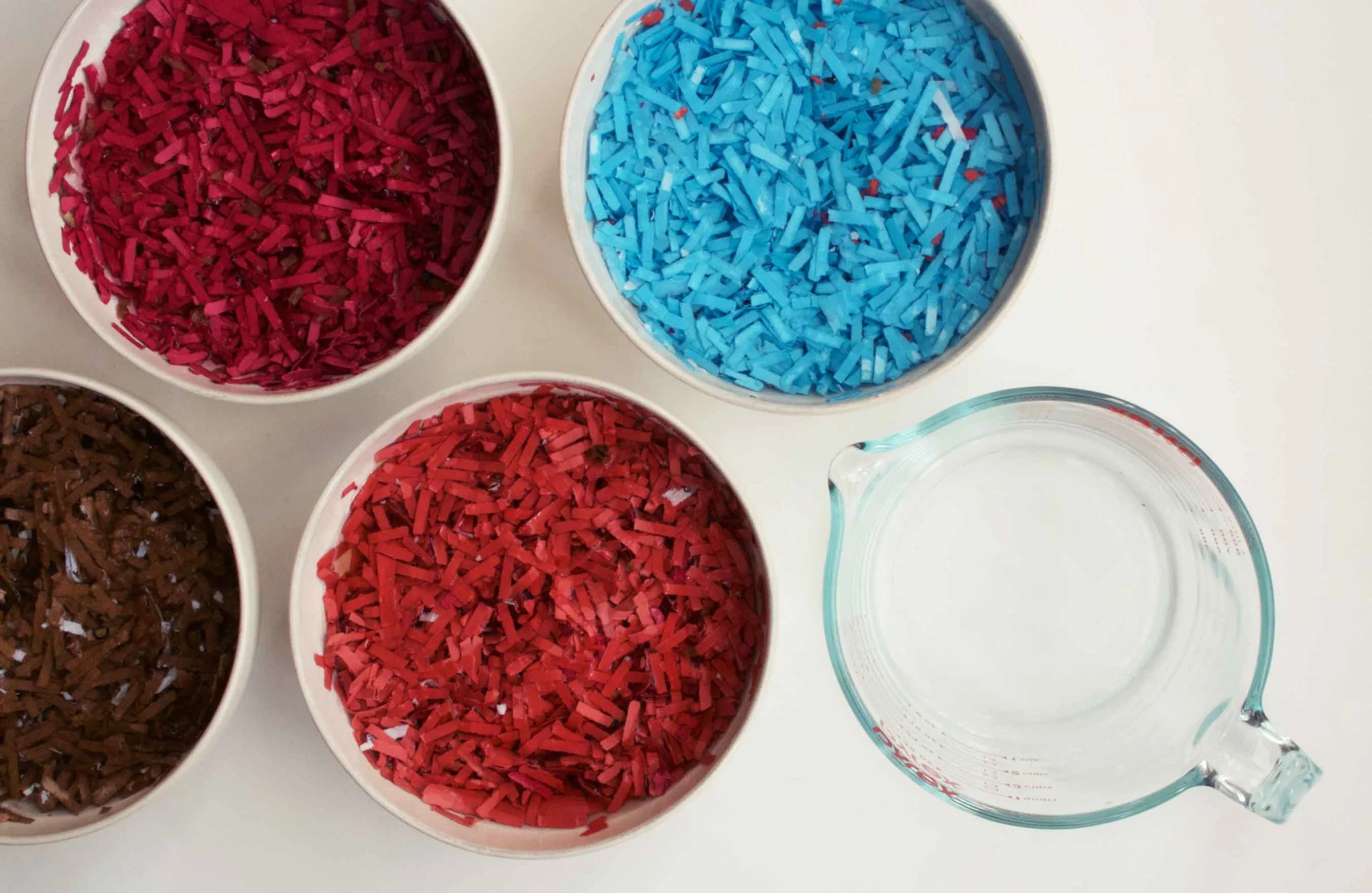 Colorful shredded papers, soaking in water to be turned back into pulp. Wildflower seeds will be added to the pulp, which will be formed into seed pebbles, also commonly known as seed bombs.
