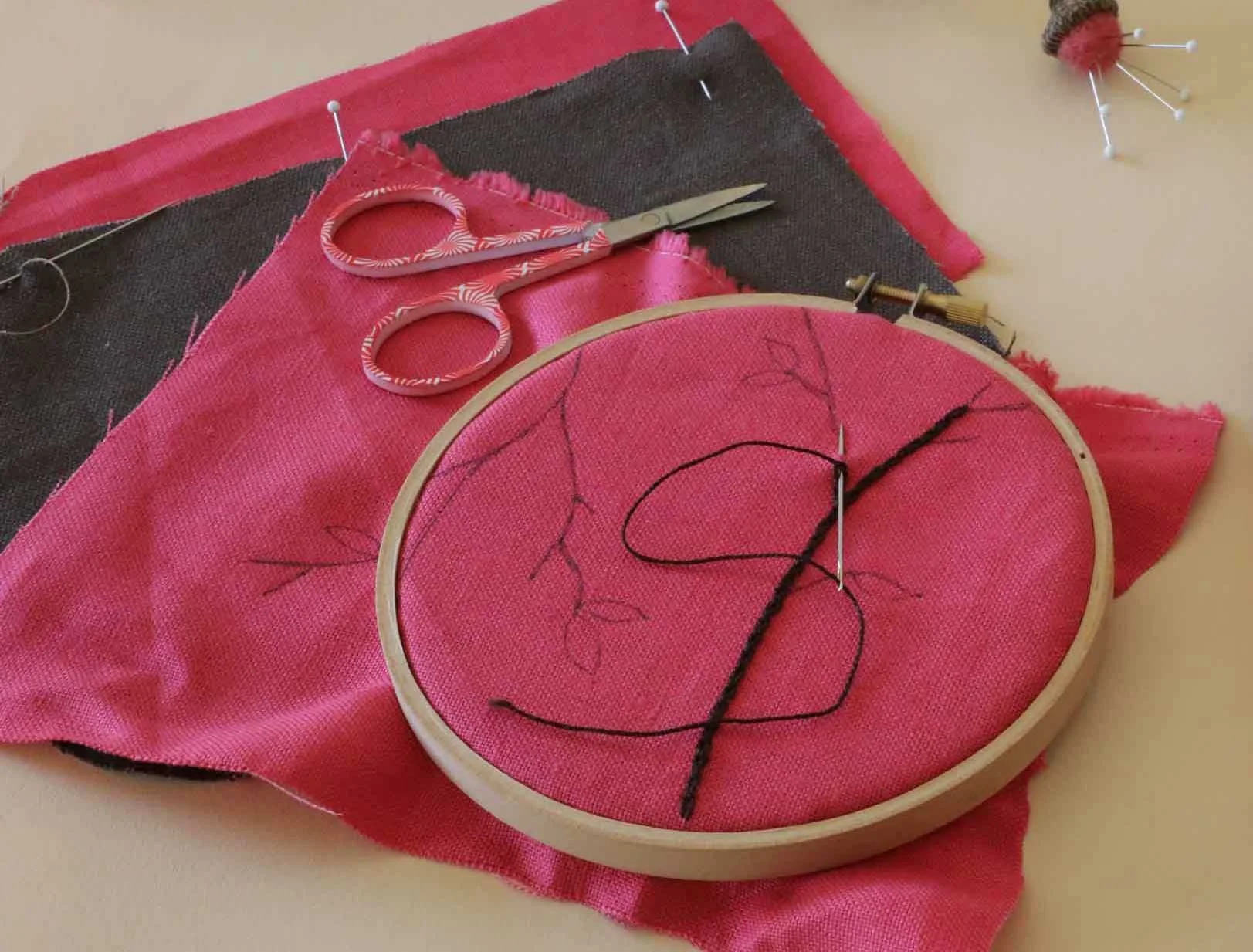 Starting a cheerful embroidery project of flower blossoms on pink linen. We have the design sketched in and the embroidery hoop ready to go. 