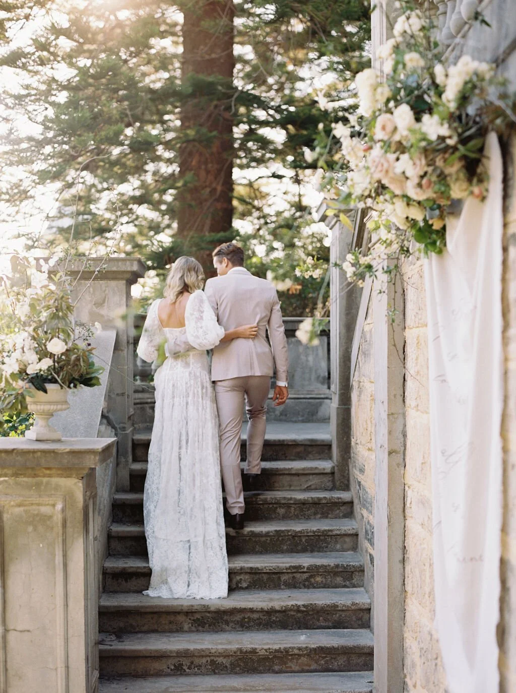 bride in lace gown walking up stairs with train trailing behind