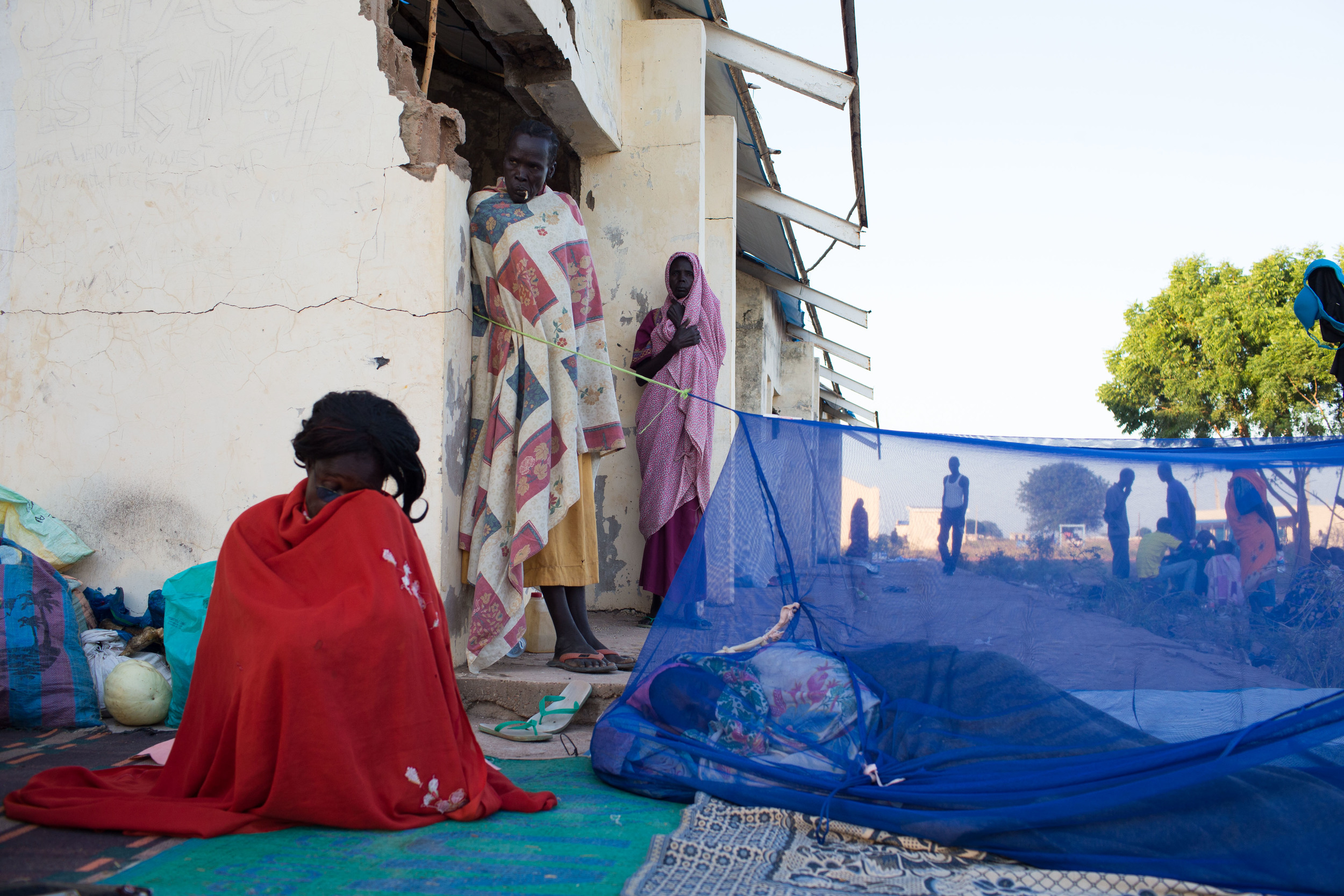  Women stay wrapped in blankets to keep warm in the early hours of the morning in Abyei. 