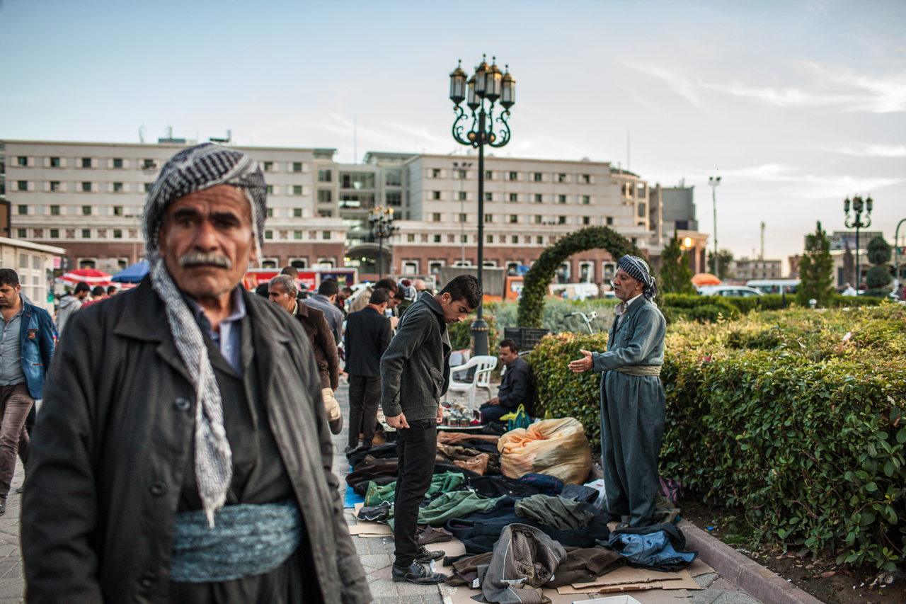 An elderly Kurdish man sells western style clothes to a young man in the center of Erbil.