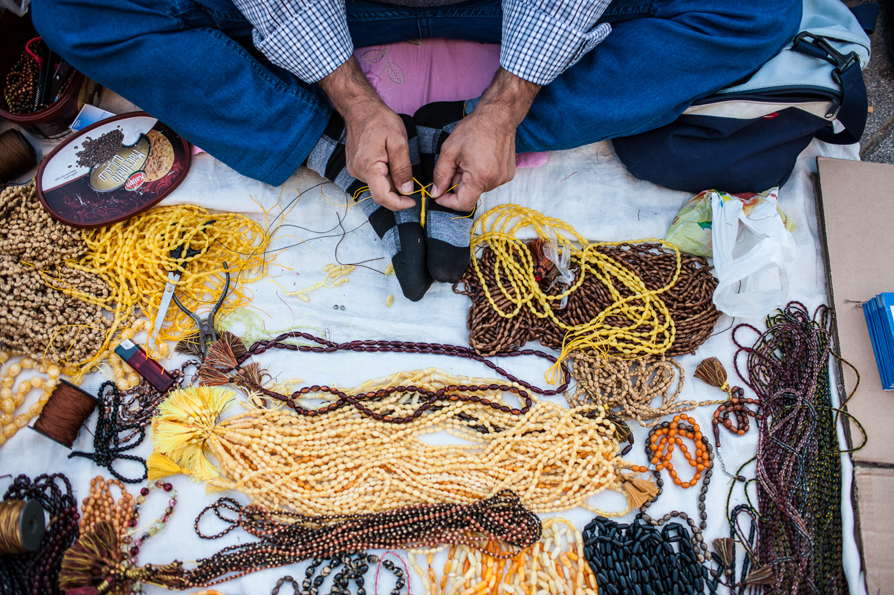 A man threads prayer beads at a market in Erbil.