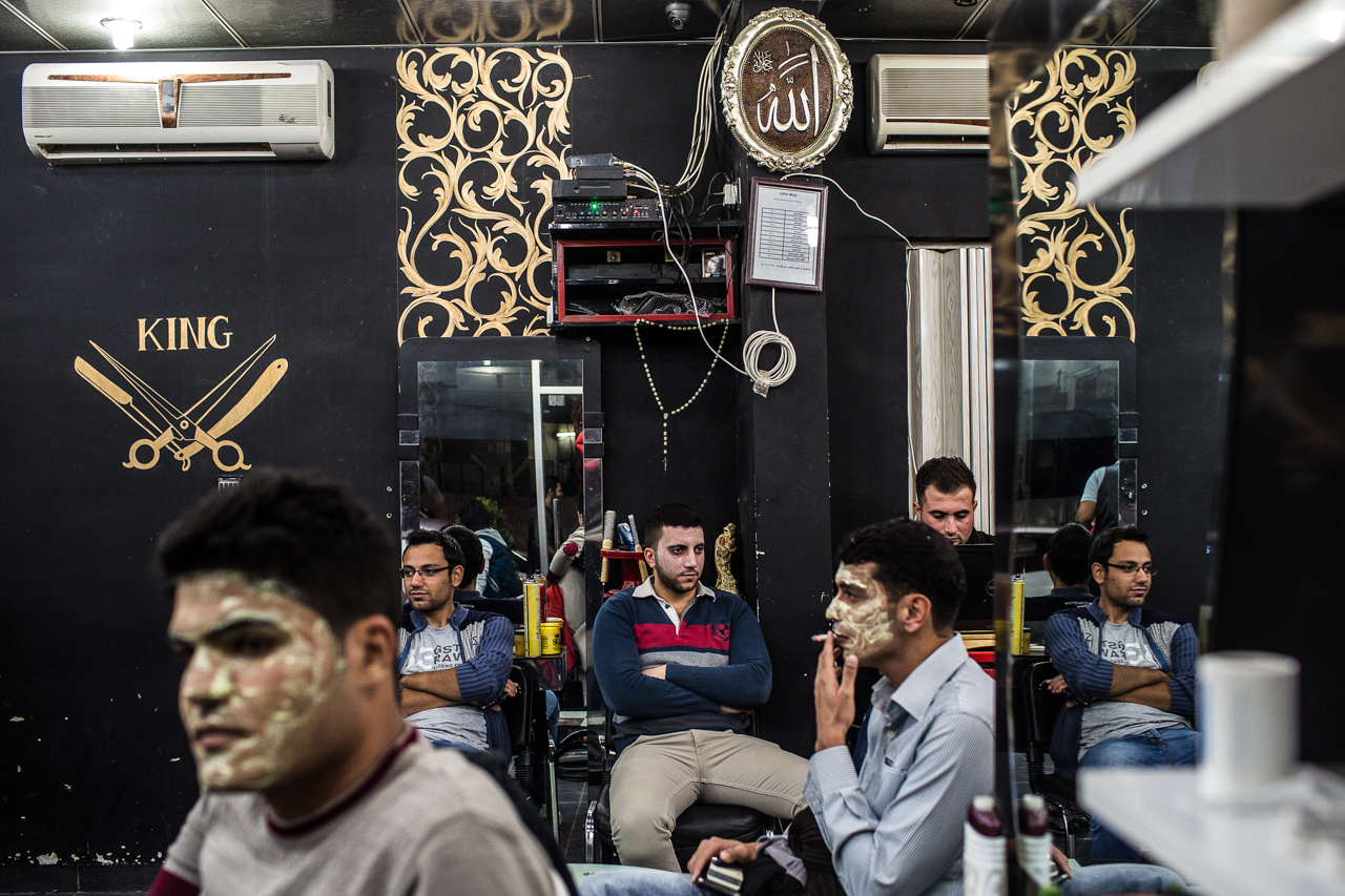 Young Kurdish men sit in a barbershop and wait for beautifying face masks to dry.