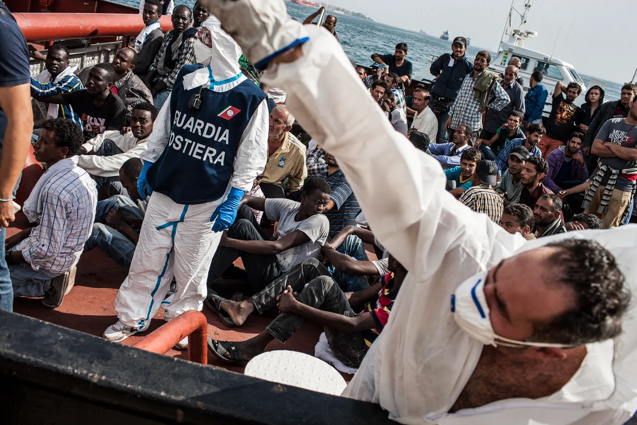 An Italian health worker yells directions as a boat of rescued migrants arrives in Augusta, Sicily.