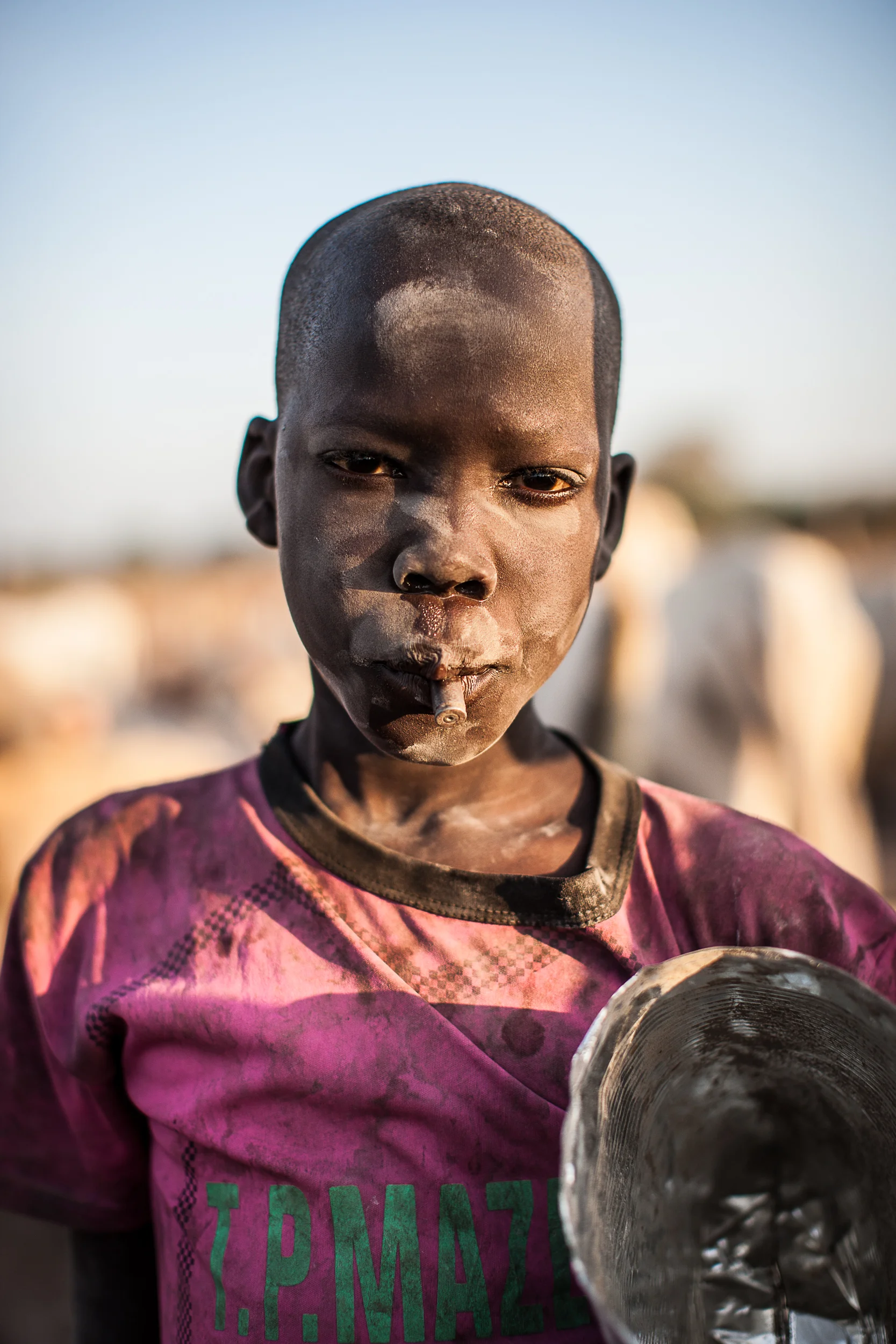 John, 13, sucks on the casing for a spent bullet in Mingkaman IDP camp where he now lives.