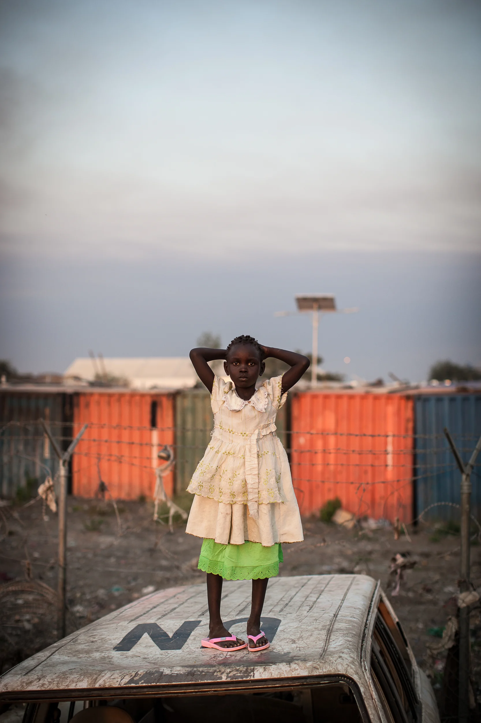 Naguna, 6, stands atop an old, broken-down UN vehicle in the Malakal PoC. She has lived there for close to a year.