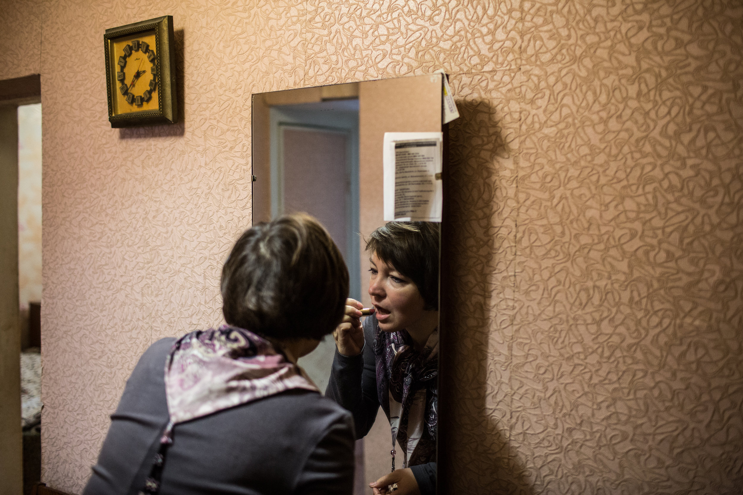 Marina, a Ukrainian language teacher by training, puts on lipstick before heading to her job running an after-school program at a local primary school. Although it took nearly a year, both her and Sasha have finally been able to find work in Kramatorsk.