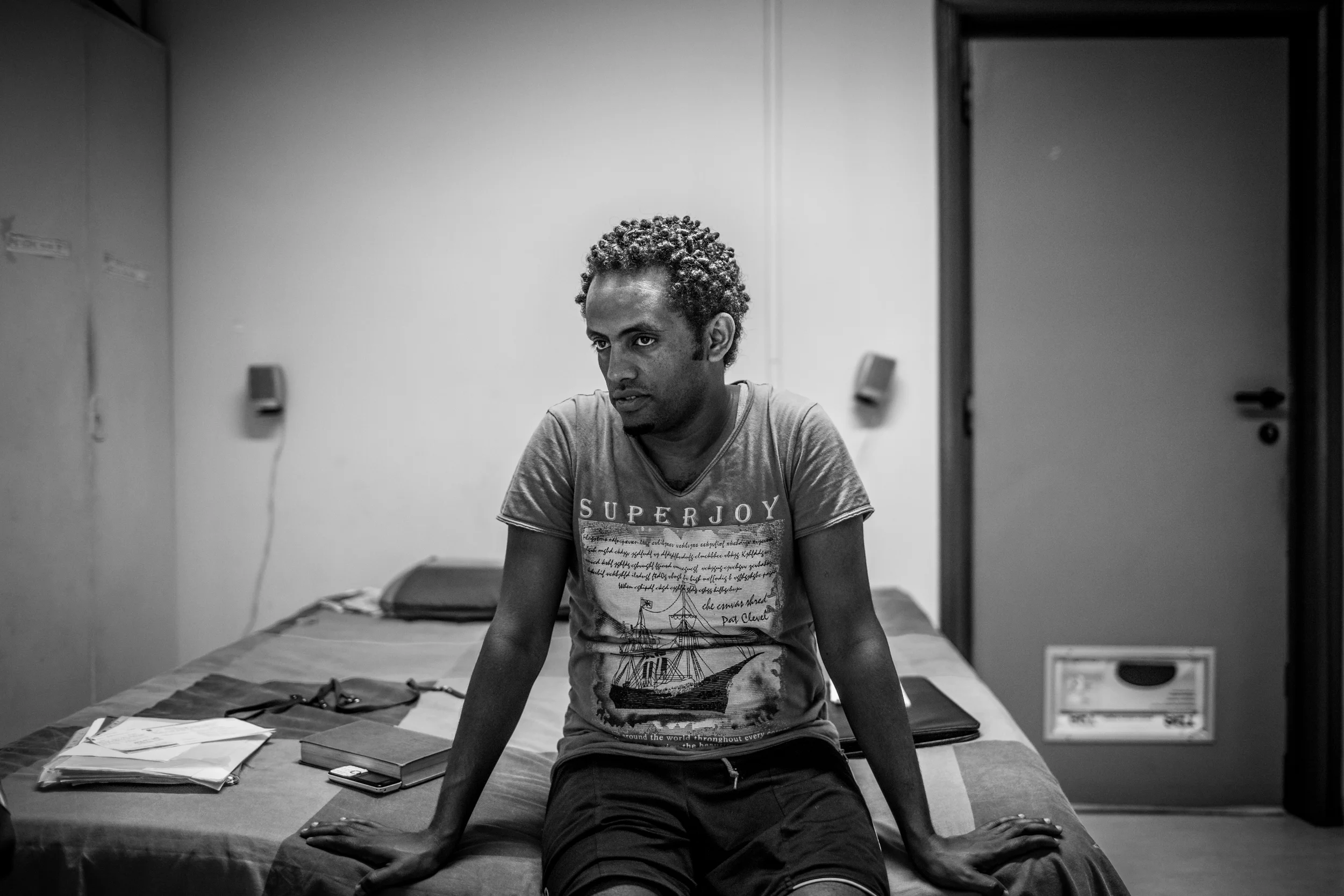 Alem, 30, sits on the bed in the small room he now calls home in downtown Rome. Like thousands of his countrymen, he fled a lifetime of military service and a dictatorial government in his home of Eritrea.