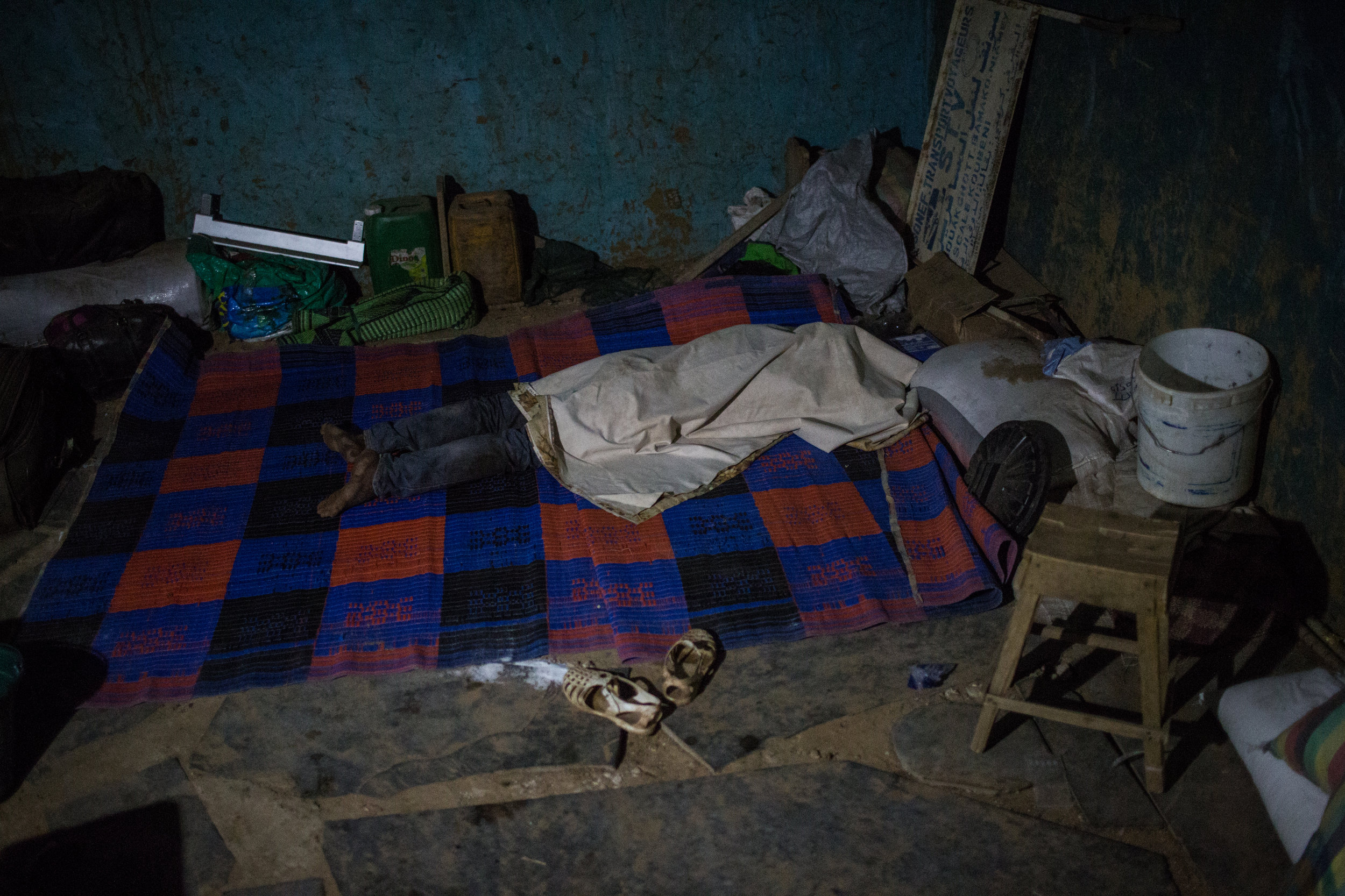 A passenger sleeps in small shed after the bus reaches the Malian border late at night.