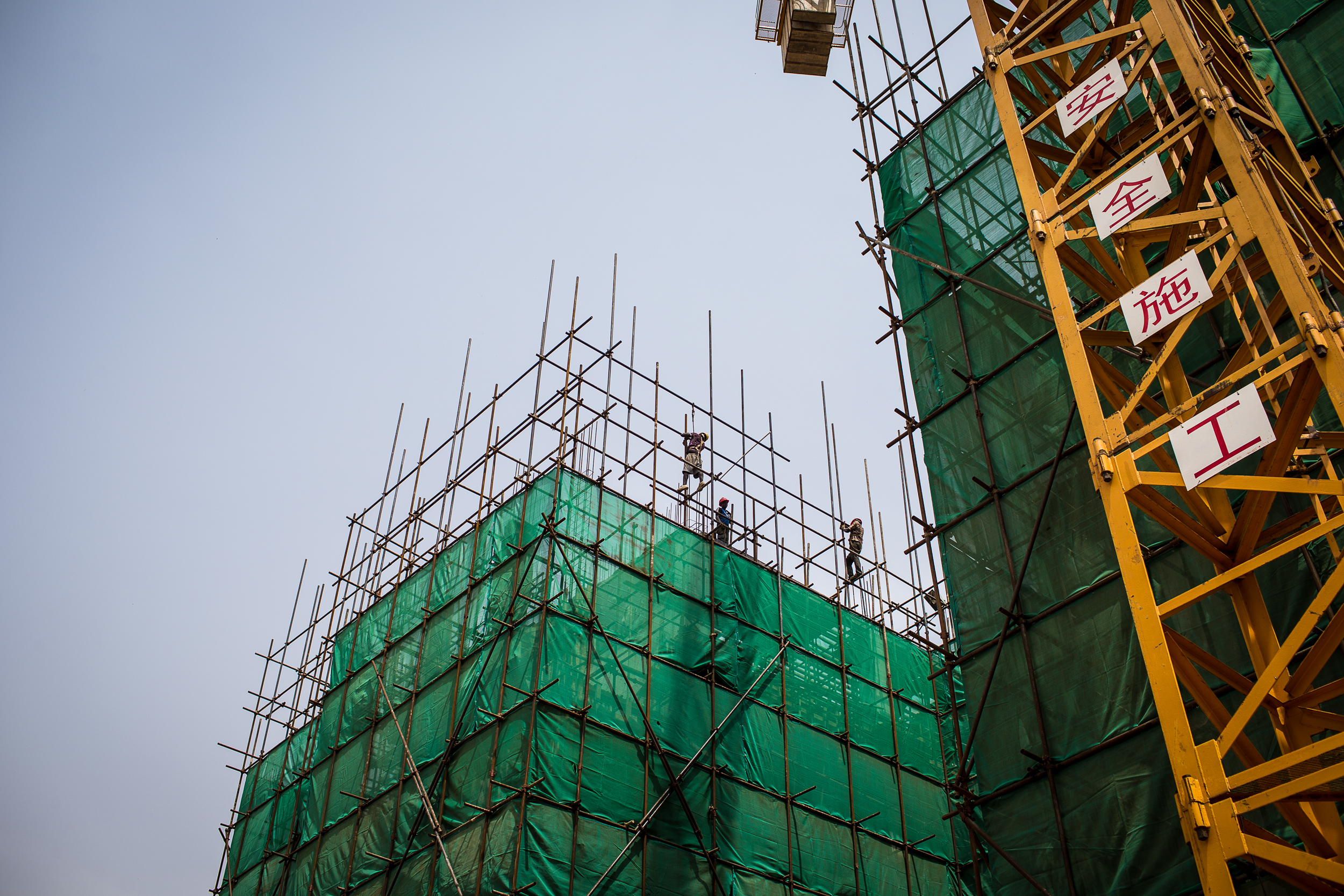 Migrant workers from neighboring east African countries assemble scaffolding surrounding the building. Enticed by steady work and higher pay, thousands of migrants from around East Africa left their home countries and flowed into Juba following the arrival of big construction crews like the Chinese.