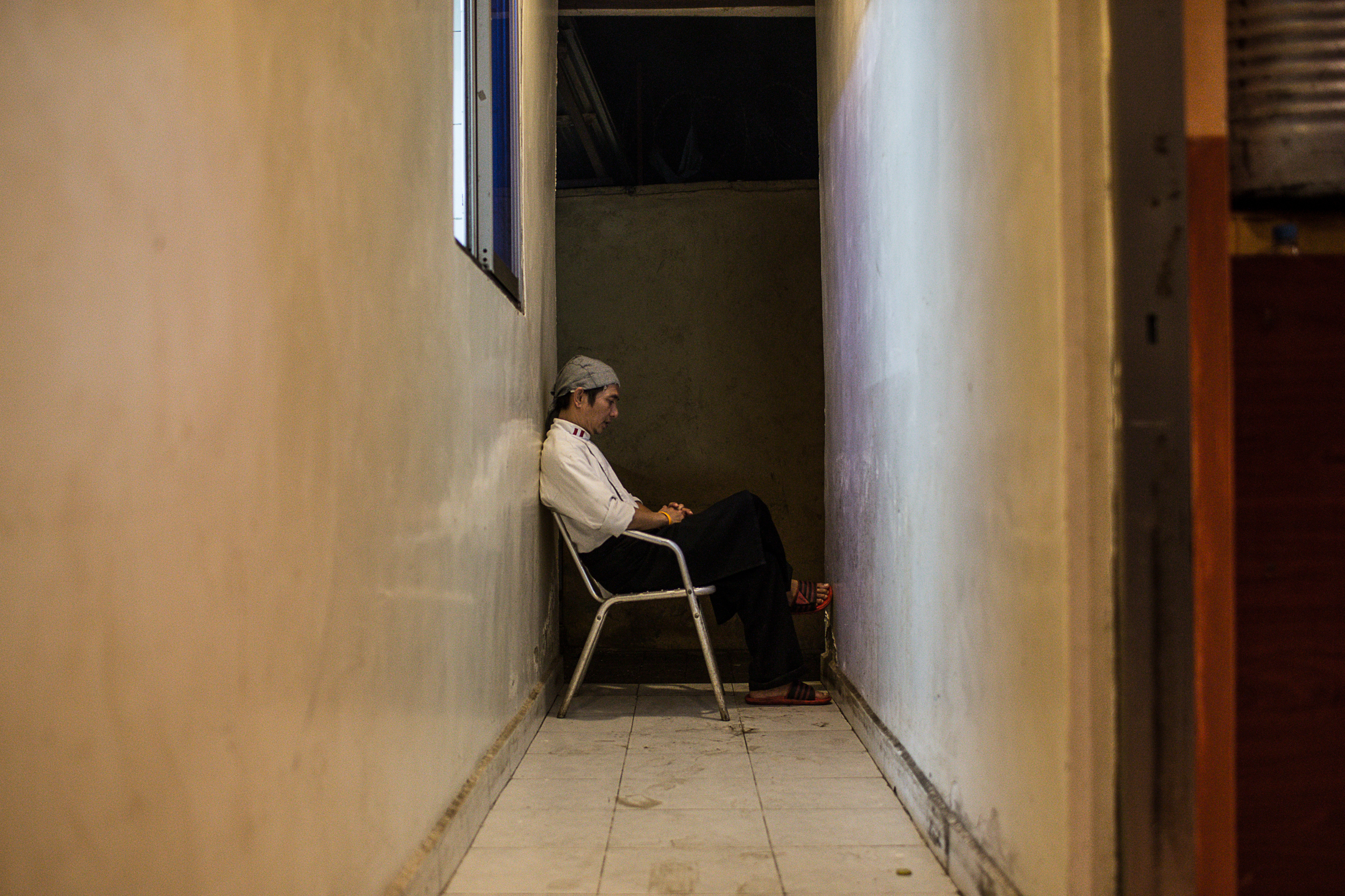 Noy takes a break to rest in the hallway behind the kitchen. "My quality of life is not so good, but the work is worth it," he says, "I can earn three times more than my salary back home and my family needs it."