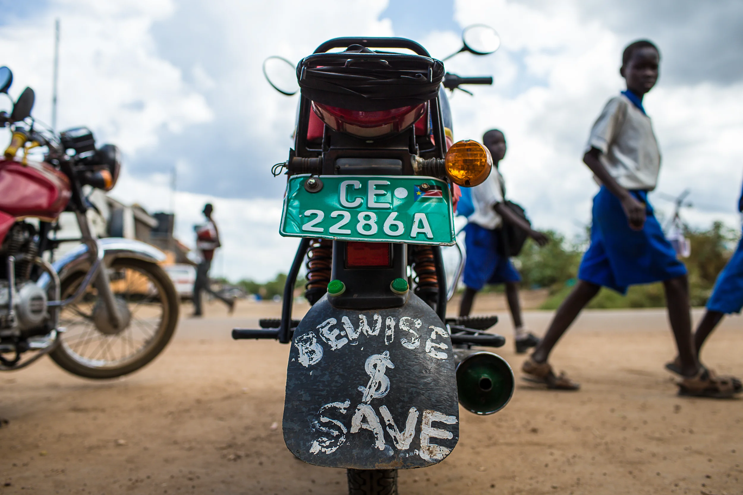 School children walk past a "boda stage" in Juba where motorcycle taxi drivers wait for passengers. Moto taxis, or "bodas", are the quickest form of cheap public transport in South Sudan.
