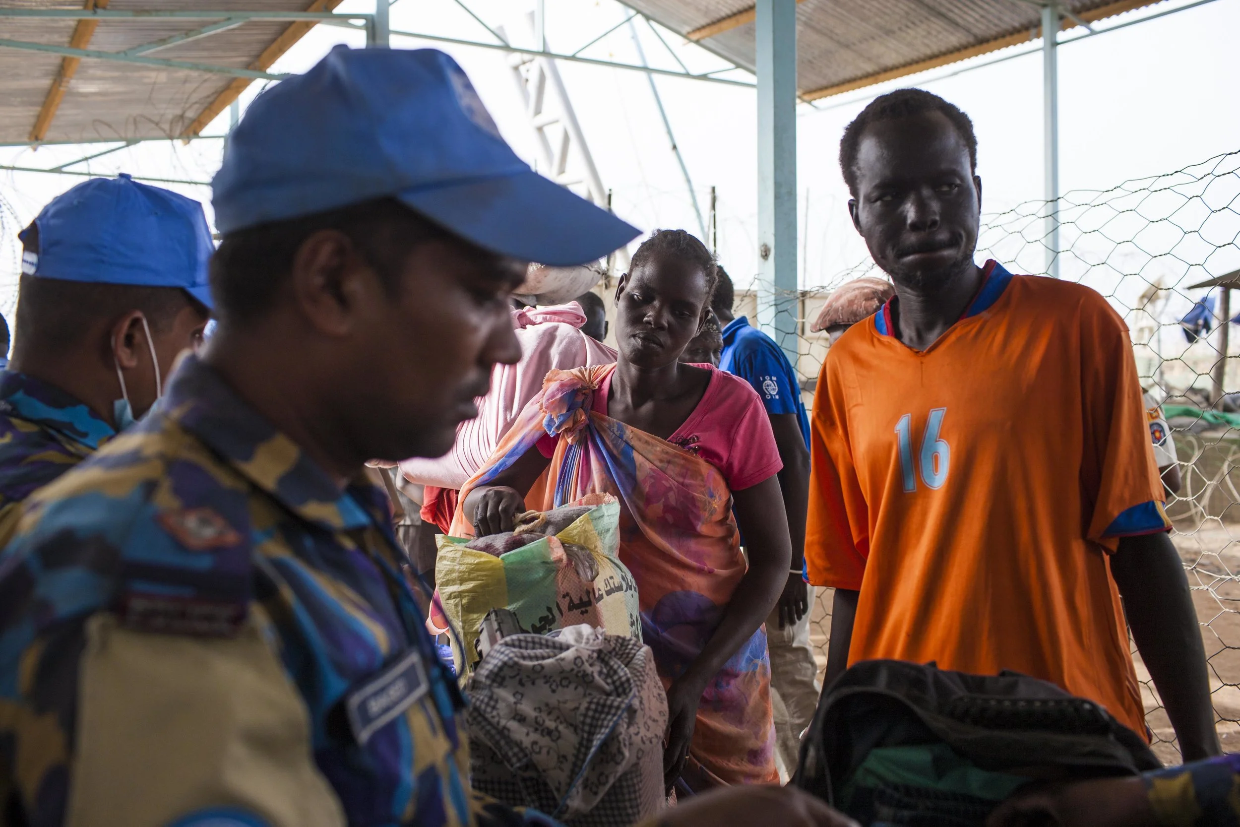 Kuany John, a teacher from Malakal, waits with his wife, Regina, as their possessions are searched for weapons by UNMISS security officers at the base entrance. They are returning after making preparations to travel north to the town of Renk the following day.