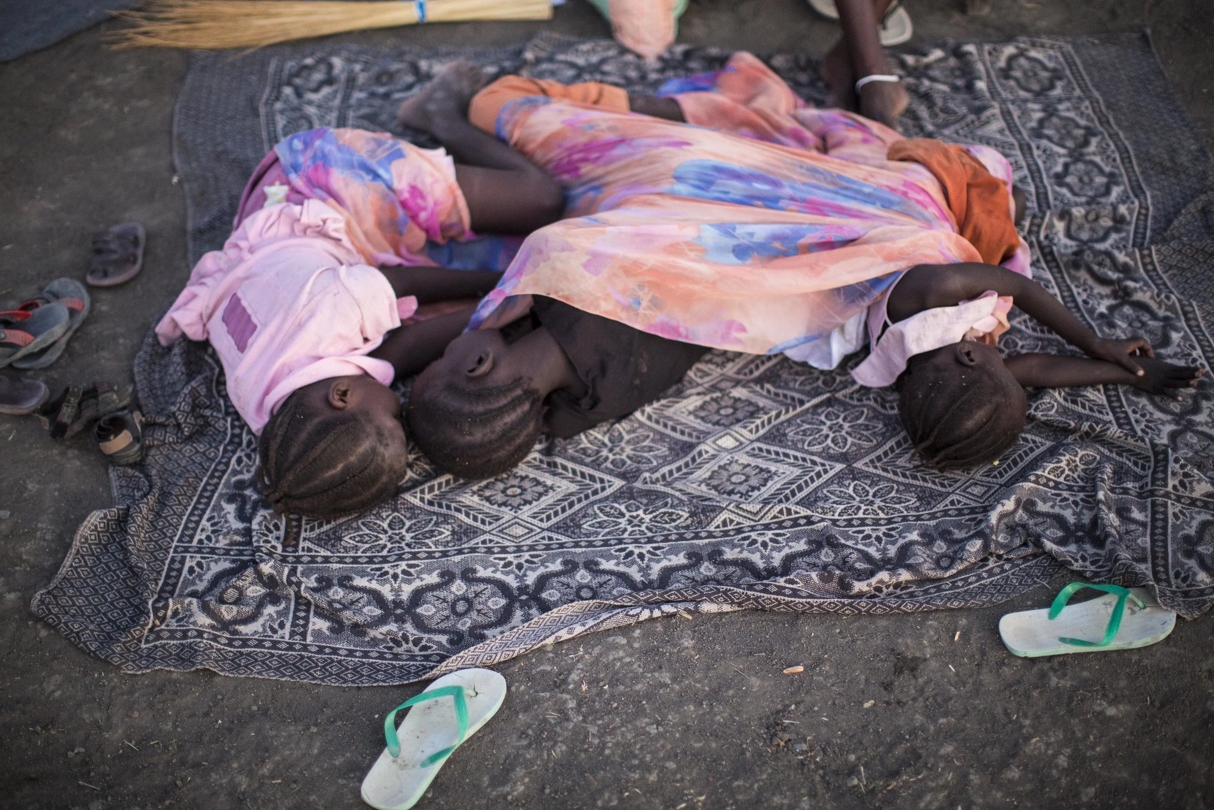 Akon, Bor, and Adut lie asleep on the side of the road the following morning, tucked together under their mother's sari.