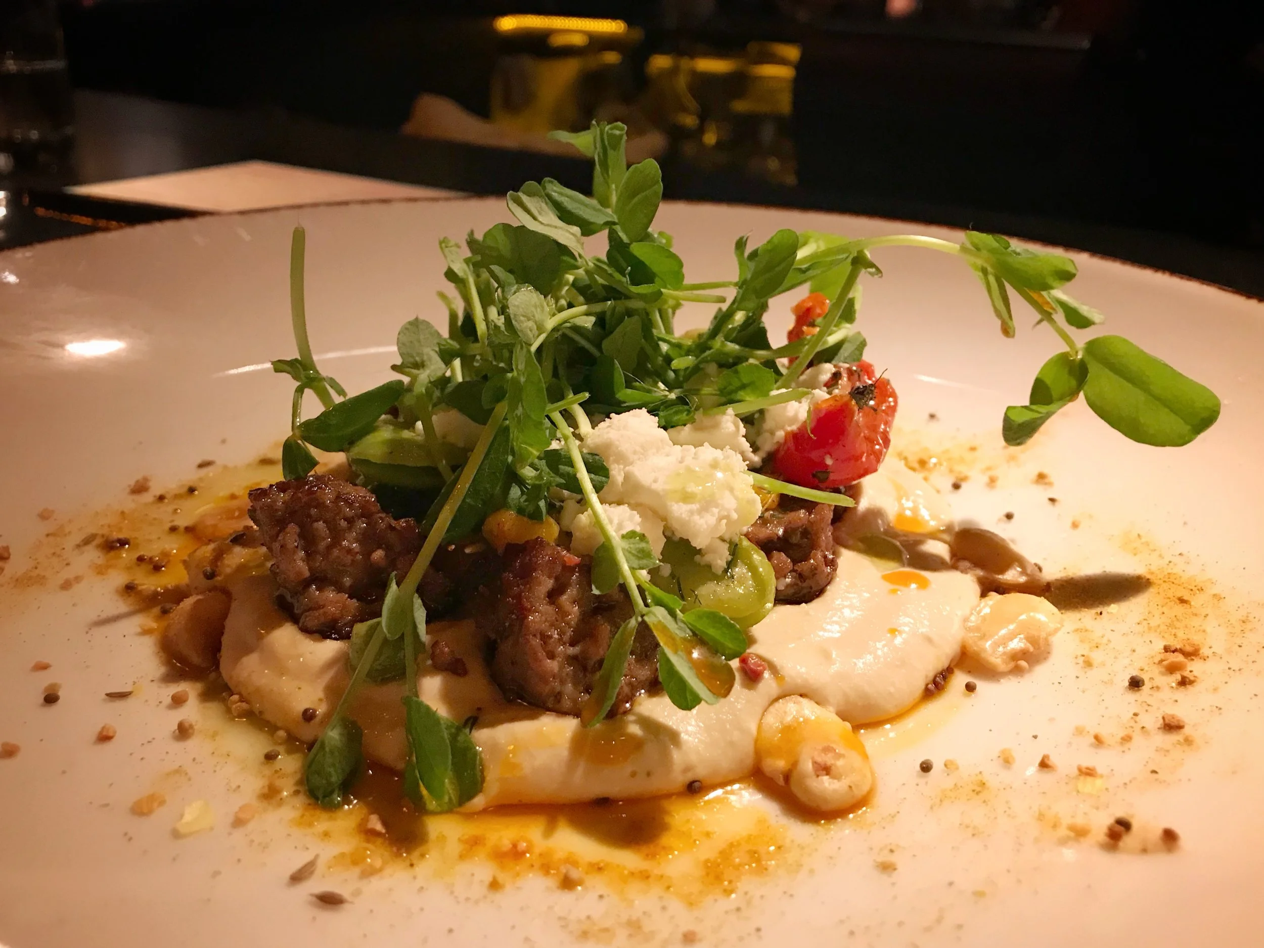Moroccan lamb sausage with hummus, feta cheese, fava beans, pea tendrils, lemon & mint