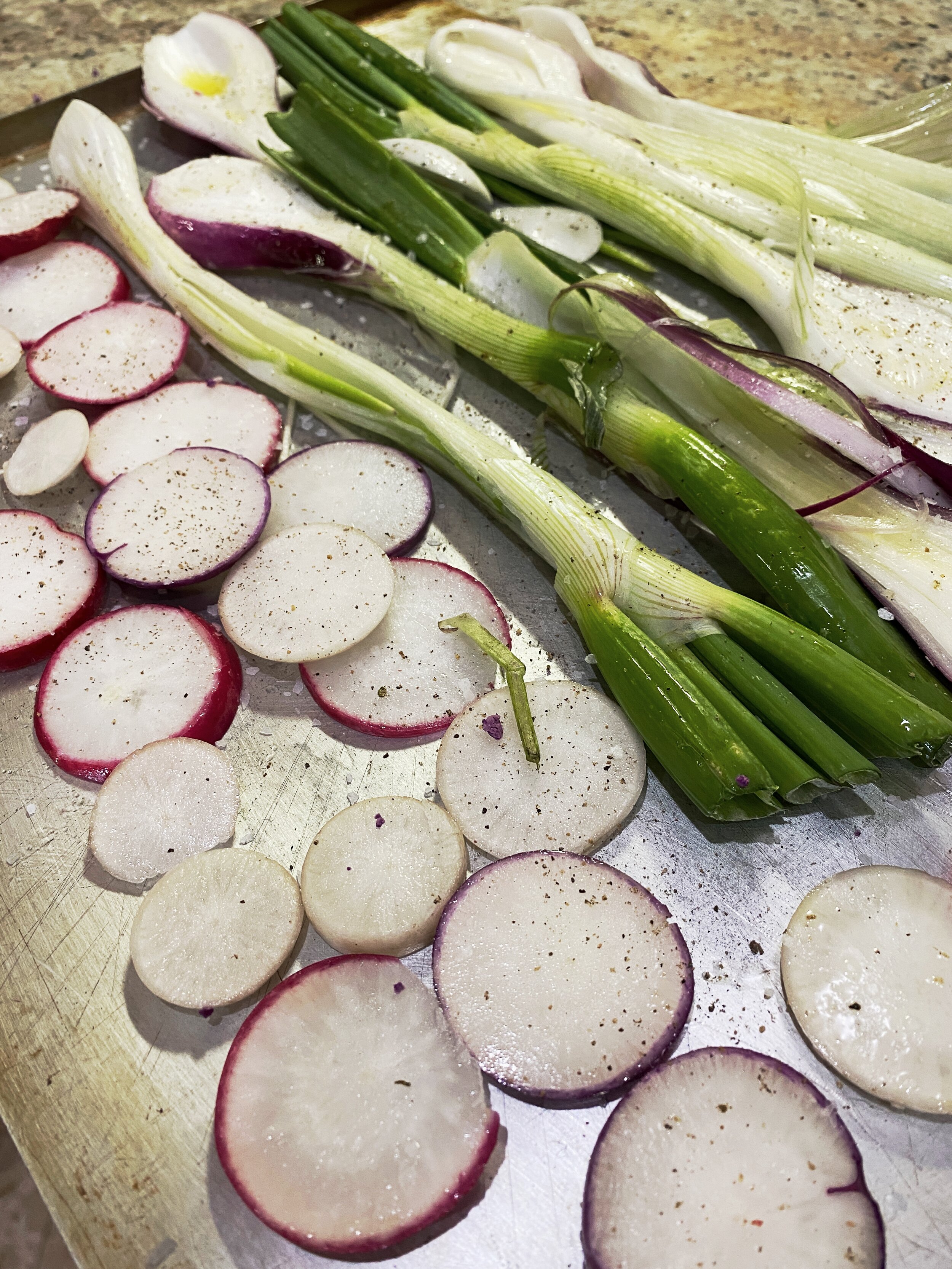 Leeks and radishes placed on a flat roasting pan