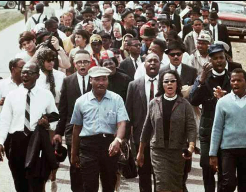Above is an original historic photo, from the March on Selma. To the right of him is his beautiful wife, Coretta Scott King.