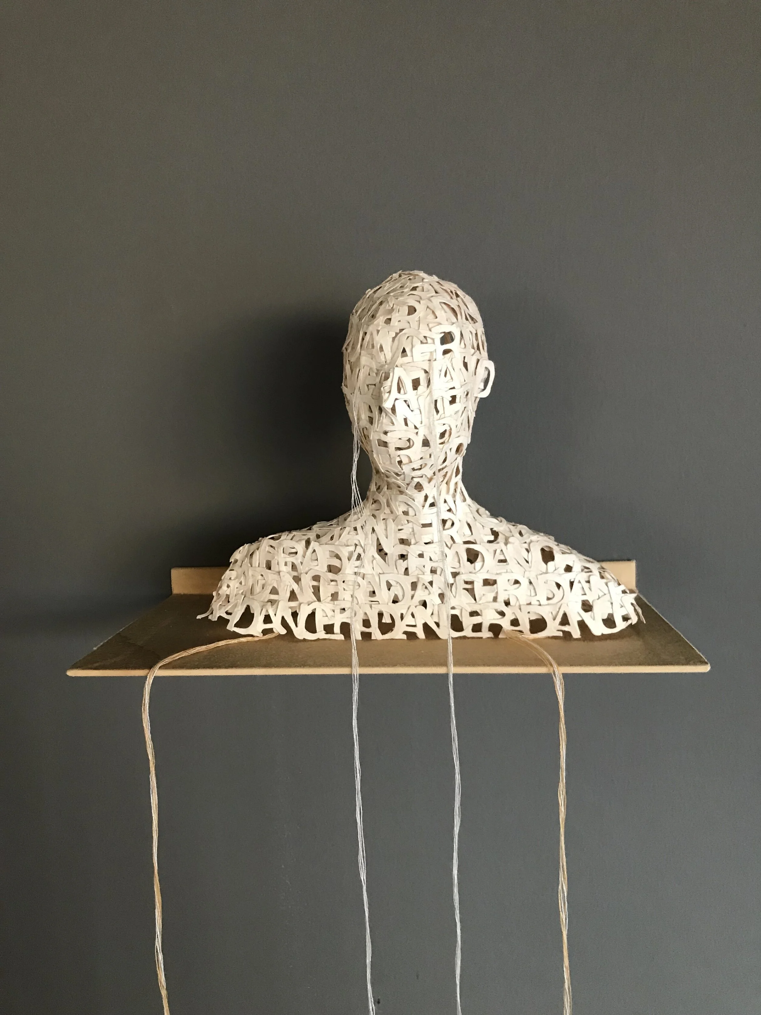 Lesley Dill, “Head,” 2003, cast, die-cut pigmented abaca paper letters with thread, stainless steel shelf covered in tea stained muslin cloth, 11/25, 6” x 7” x 3 1/2”
