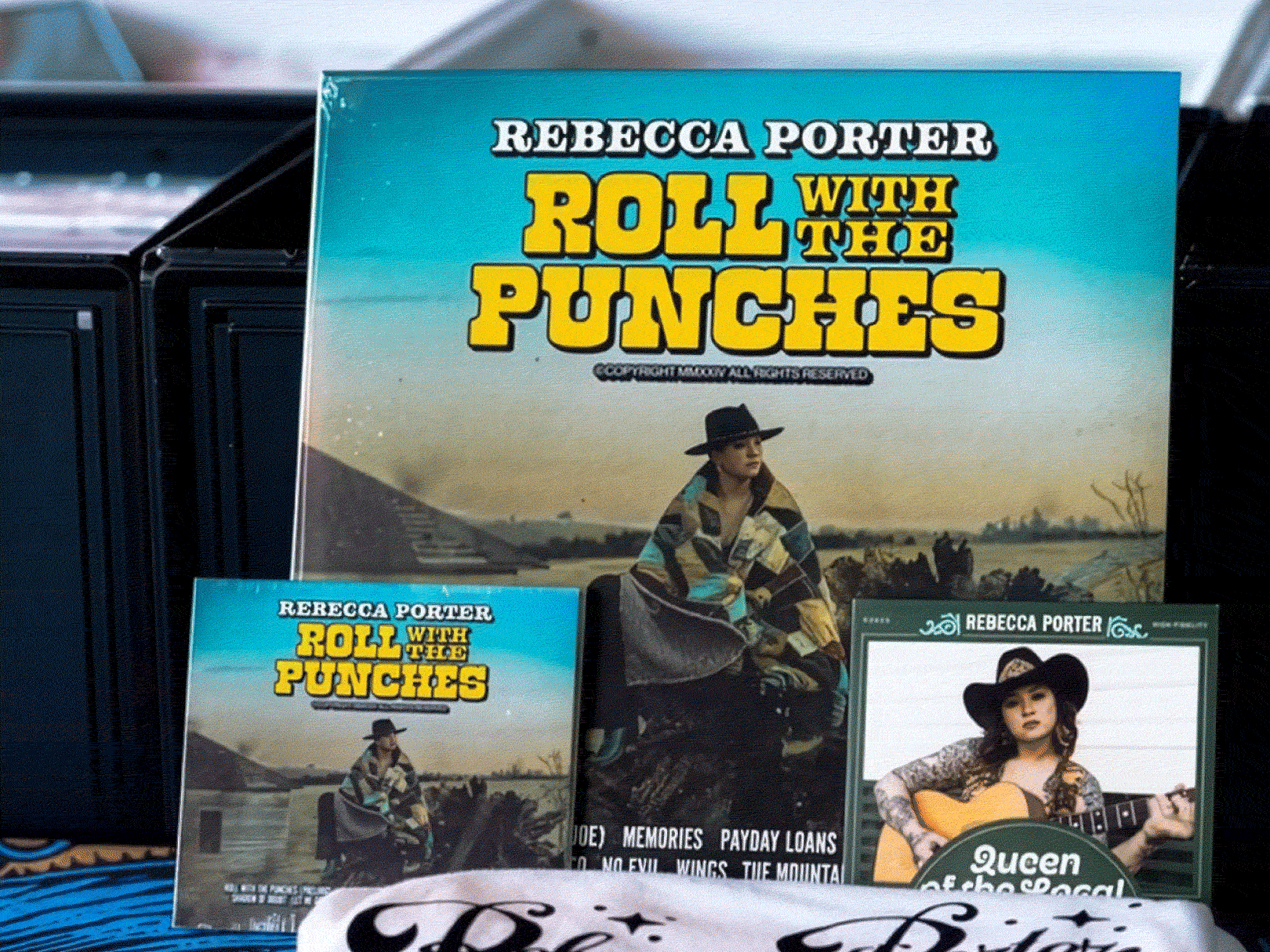 Books by Rebecca Porter, including 'Roll with the Punches' and a music album with a woman playing guitar, displayed on a table.