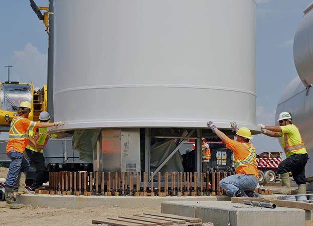 Source : ReNews 'Champagne Flows at South Kent '. Attaching base section of wind tower to foundation