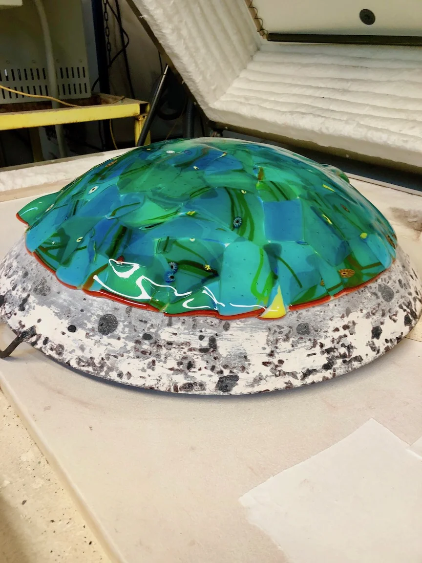 Taken up to around 1200 degrees F. the glass lays down, “slumps” into place and now is the dome when its hung up. strini art glass. 2108