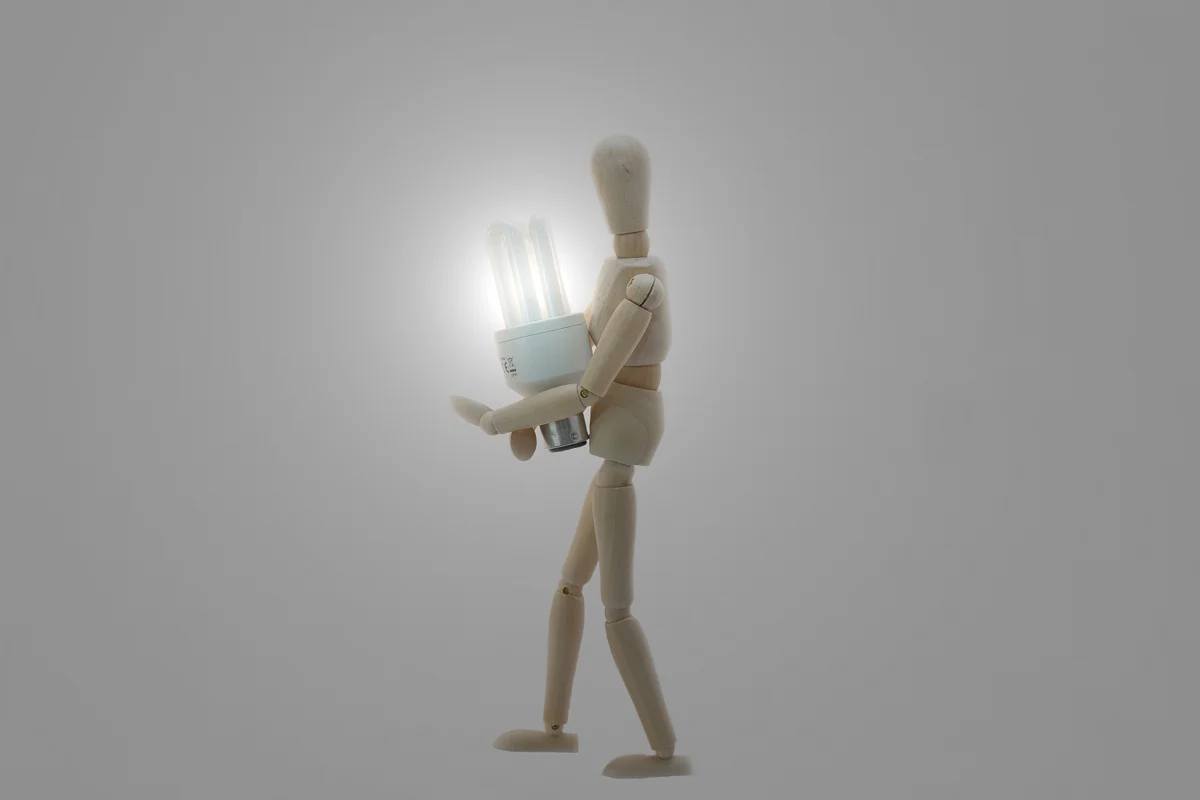 Wooden Manikin Doll Holding Low Energy Bulb