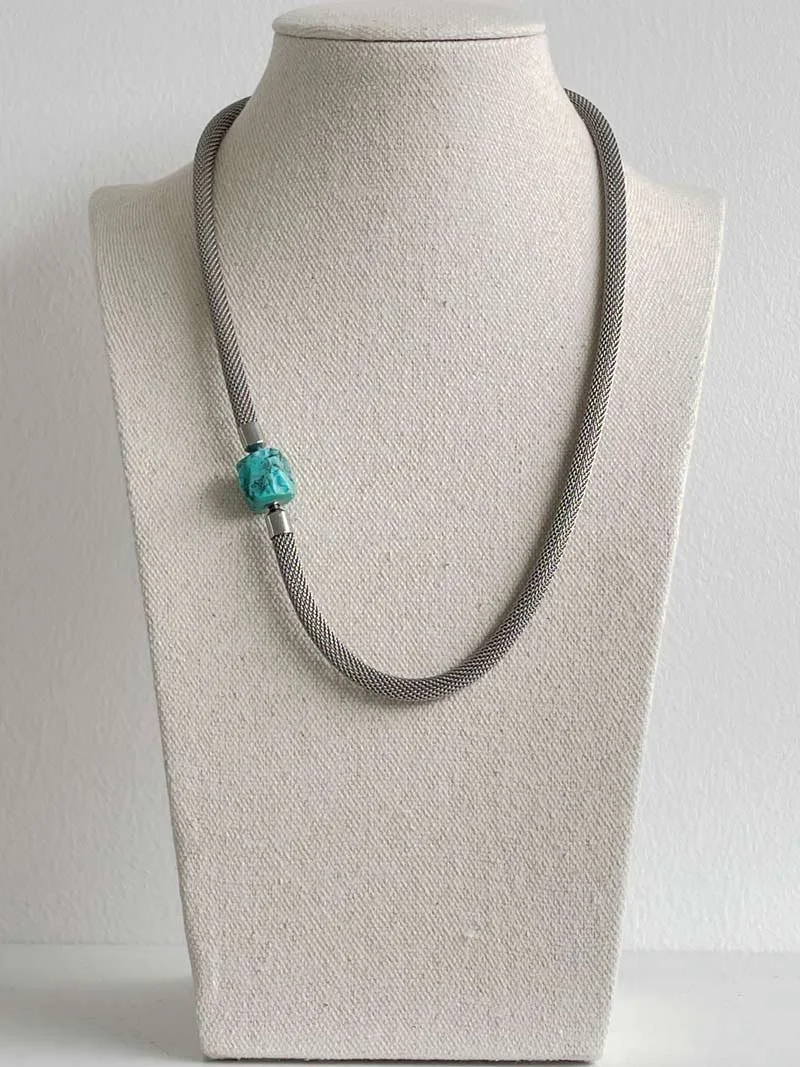 Steel mesh necklace with small blue green interchangeable turquoise nugget feature clasp pictured on a linen bust