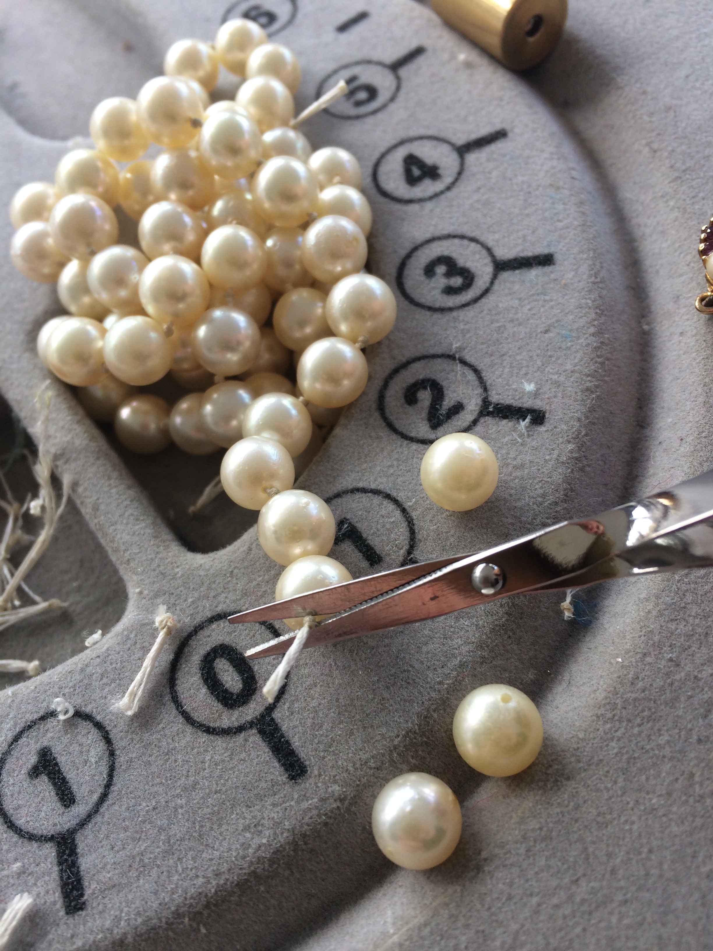 Cutting each knot to remove the individual pearls