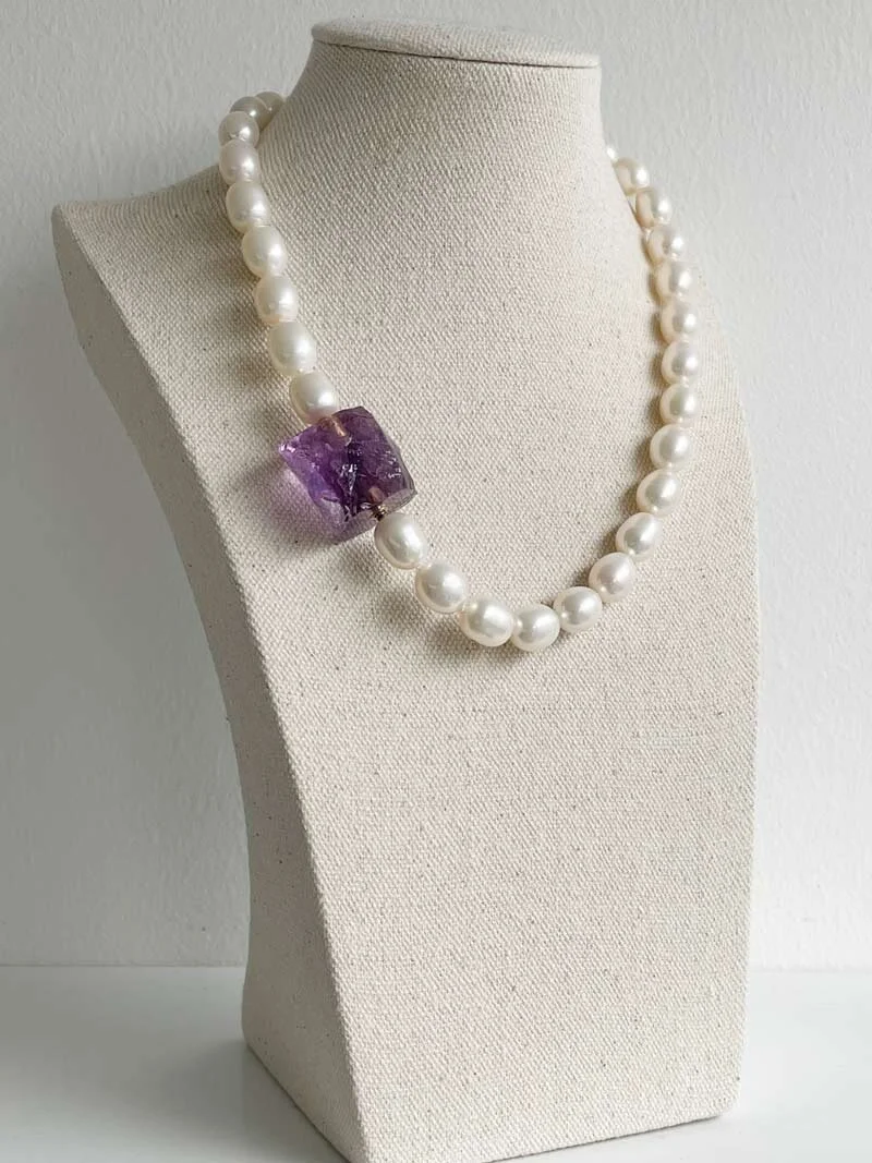 Oval cream pearl necklace strung with knots and closed with a fuly detachable amethyst nugget clasp | Clasped
