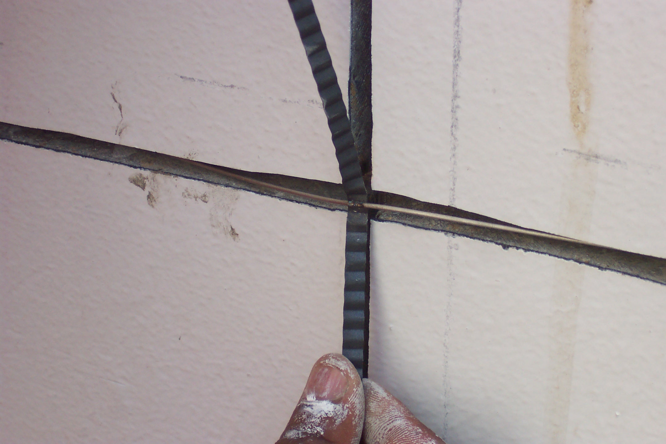 The installation of coated titanium ribbon anodes into slot. The system is for an existing concrete structure.