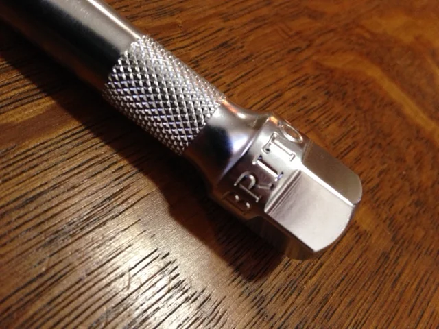 A ratchet extension with a knurled section and a hex fitting for wrench.