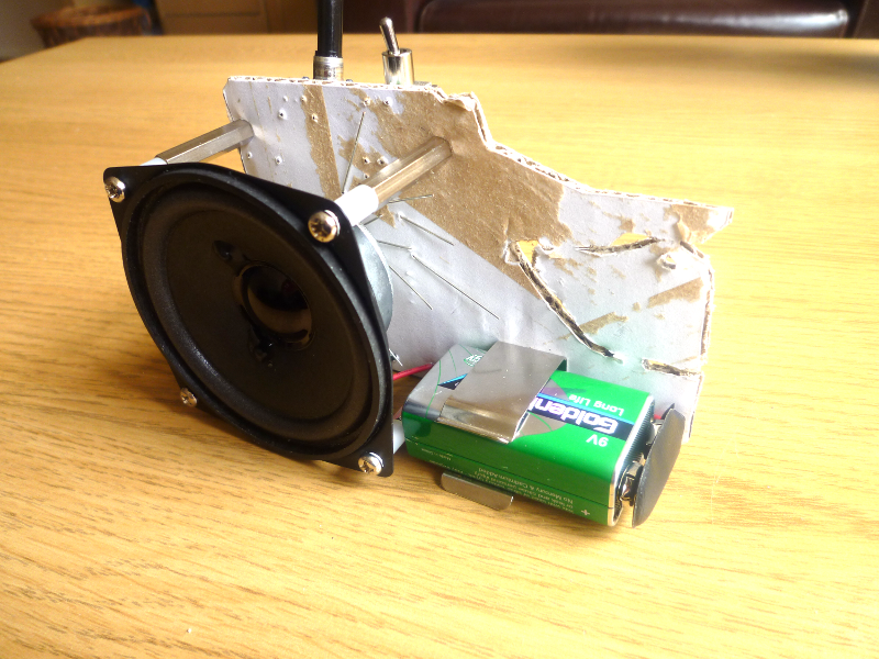 The battery is held by a metal clip so it doesn't hang. This also provides support for the board. Most importantly, it doesn't show from the front, as you face the board.