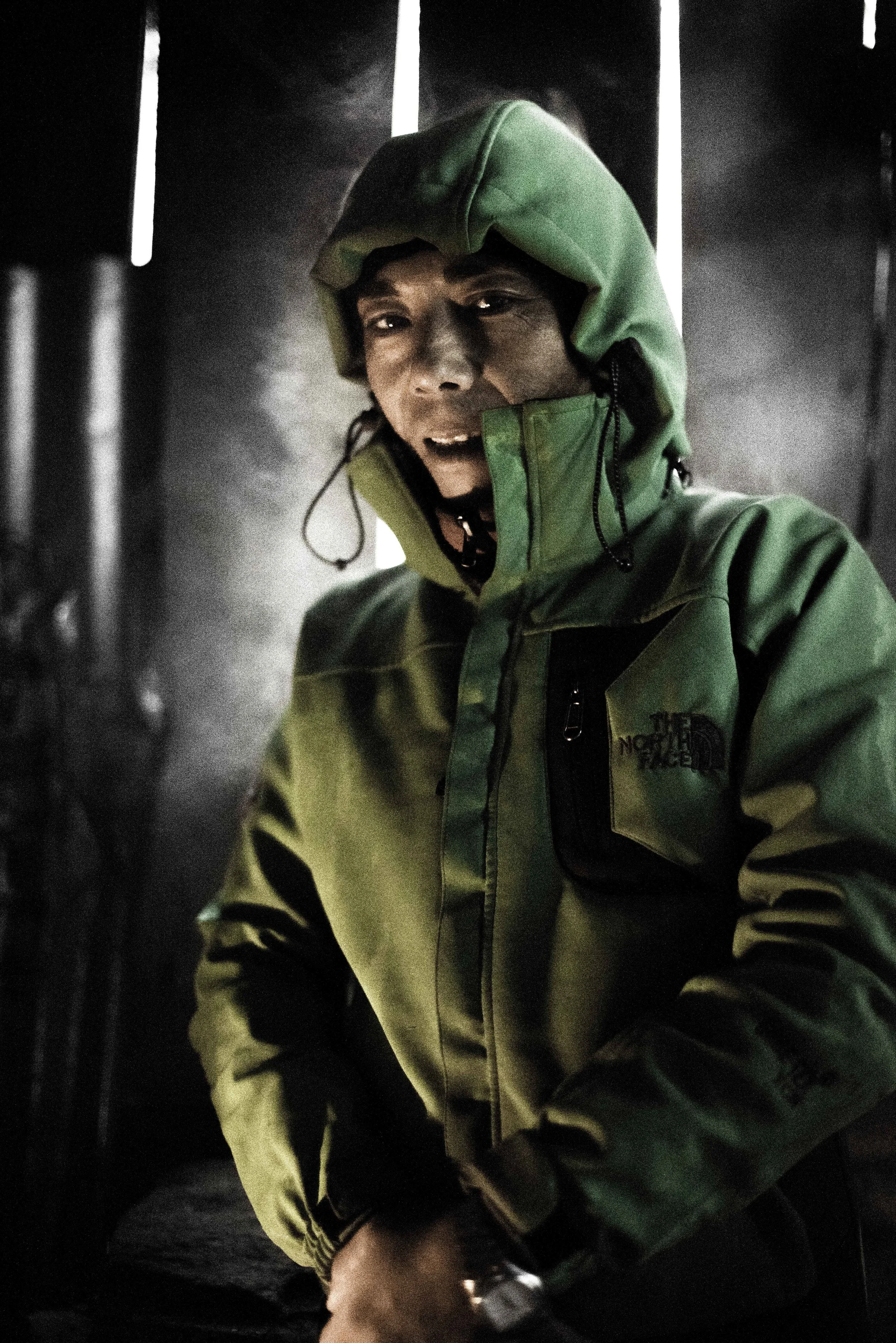   Dorje from Okuldhunga comes towards the warmth of a fire after rebuilding the roof of Cheten and Babu Tamang's house during a storm, his jacket steaming. He eats and sleeps in this temporary hut.&nbsp;    Many workers from other regions have come i