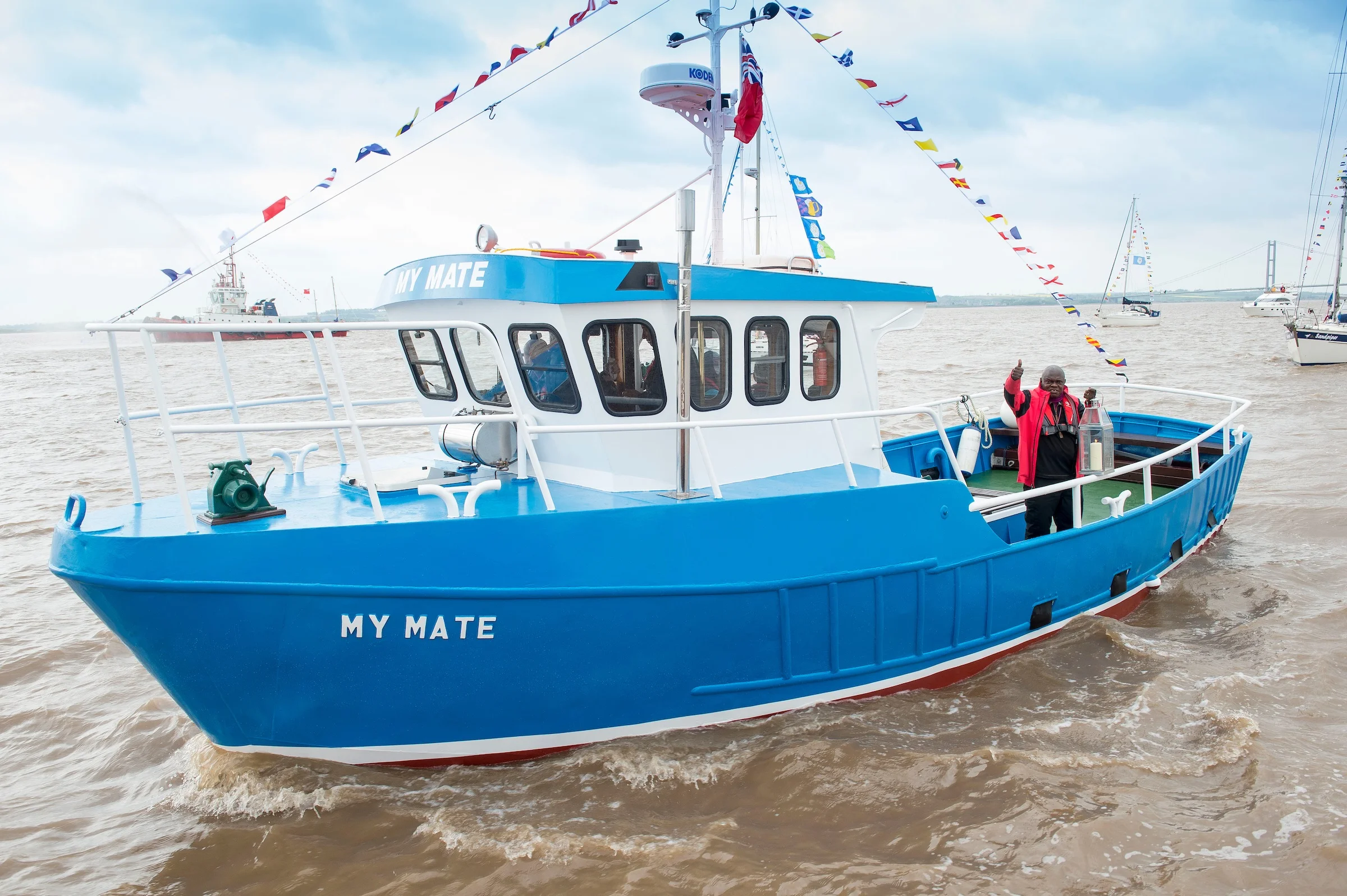 The Archbishop carries a lantern from All Saints Church on board the trawler My Mate at the head of a flotilla of vessels on the Humber estuary.