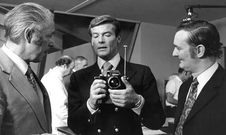 Roger Moore's James Bond (centre) checks out a camera rocket launcher in the 1974 film The Man With the Golden Gun. Photograph- Allstar/Cinetext Collection/Sportsphoto