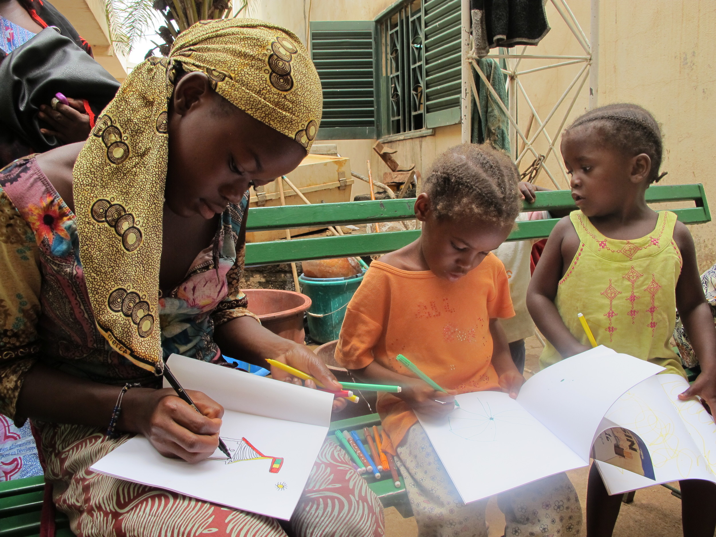 Kids, who have grown up HIV free thanks to GAIA's mother to child transmission prevention program, draw while they wait for lunch to be ready.