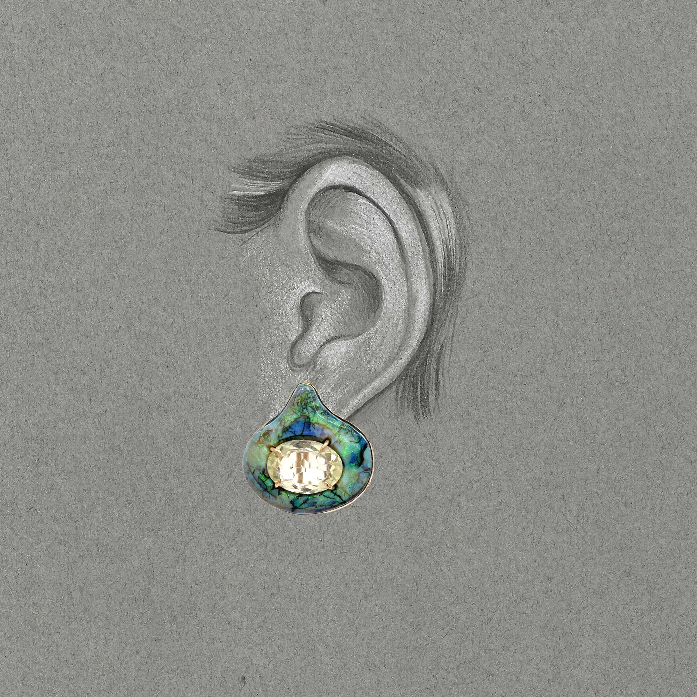 black and white drwaing of an ear with green and blue clip on style earring