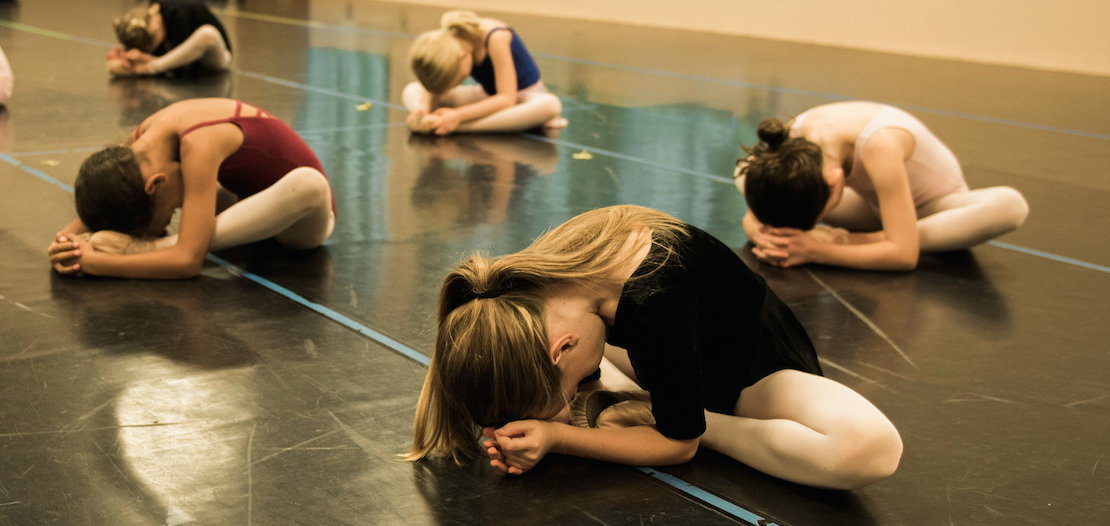 While these dancers are all doing the same stretch, notice that some dancers' knees are higher or lower and the feet are placed at varying distances from the body. Variation is crucial in healthy stretching.