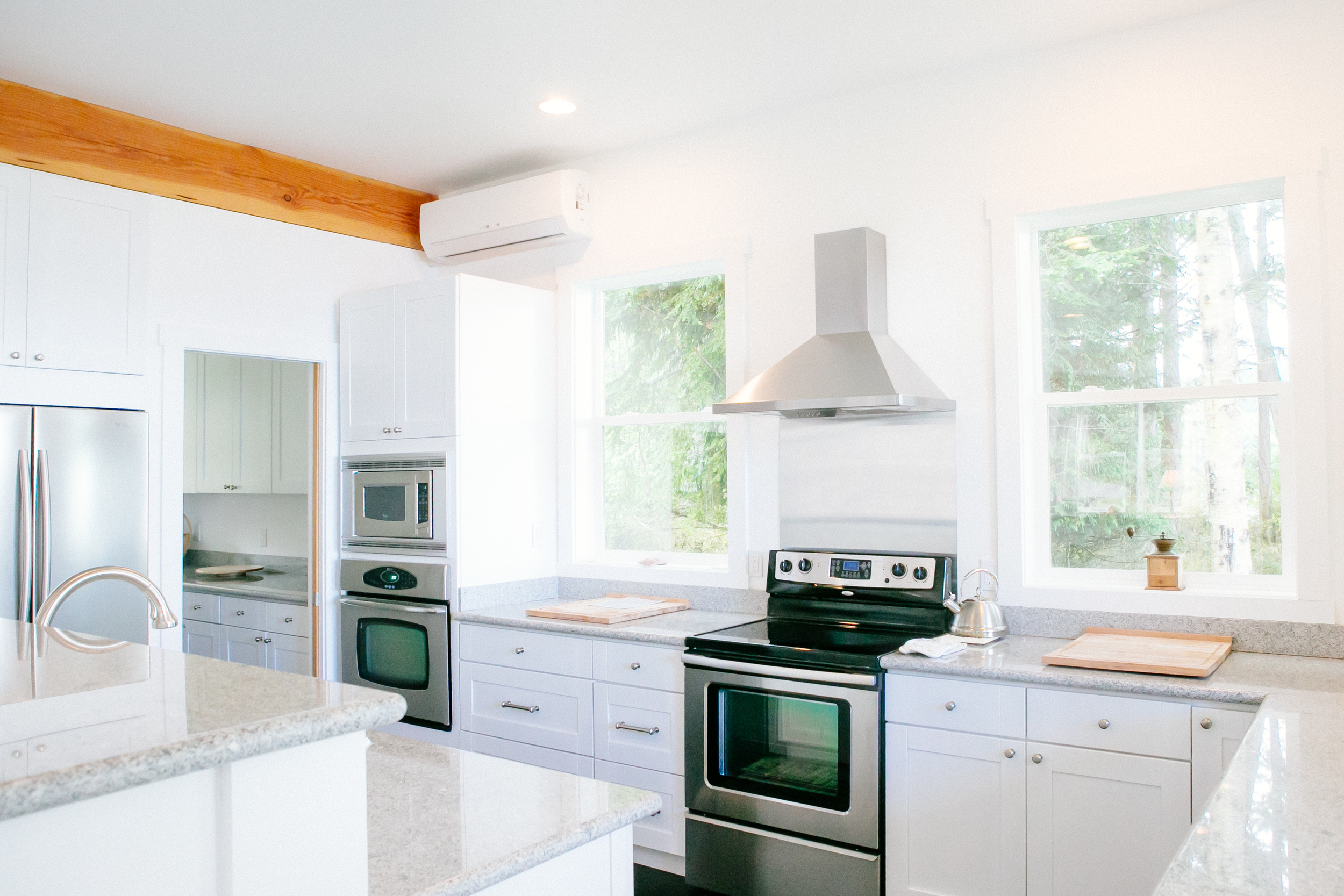 to maximize this kitchen's connection to nature and light, we designed it with lots of large windows and few upper cabinets. the adjacent pantry more than makes up for any lost storage space.