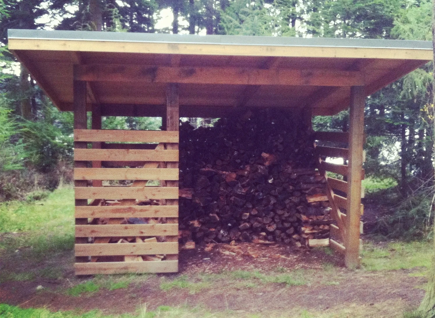  This woodshed is about as efficient as it gets: six posts, four beams, car decking roofing, and firewood. 