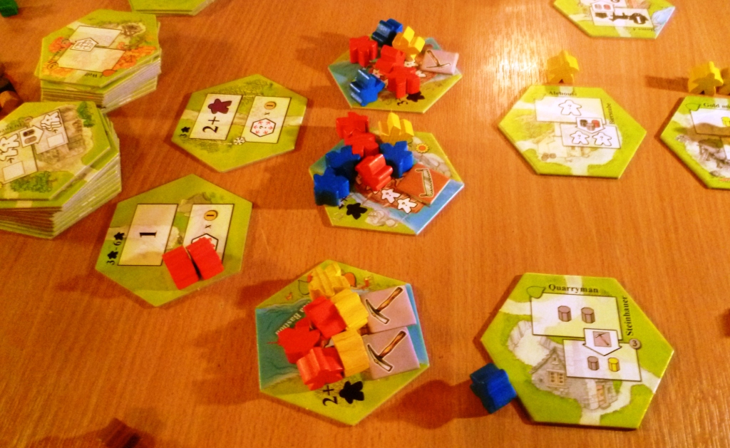 From the left :- Stacks of cards for later in the game, Turn order cards (SE player has bid 1 red for first place next turn), incoming boats with more citizens, tiles out for bidding for this turn.
