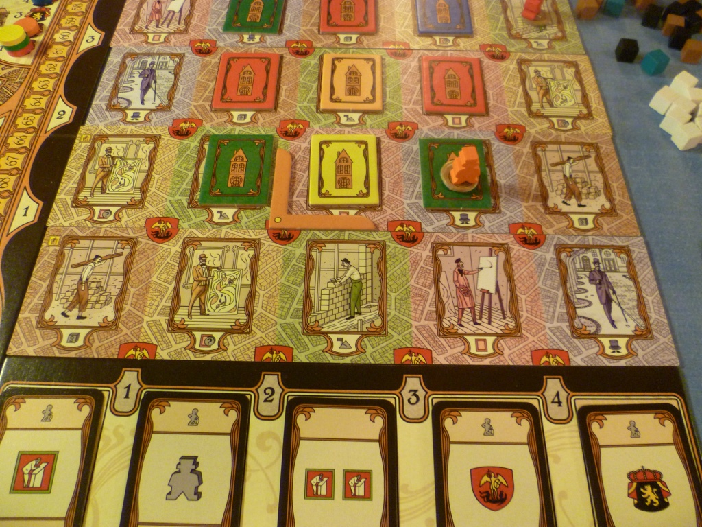 Mid-game. This part of the board showing one of the worker placement areas with some buildings erected and at the bottom of the screen bonus cards for column control. The "L" shape indicates the area of the board currently in play.