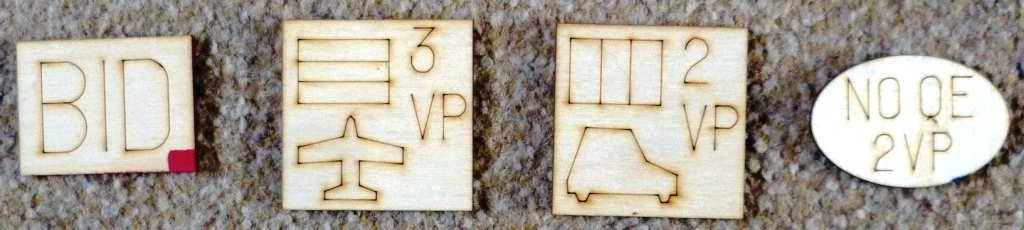 Some of the wooden tokens in the game, the two middle are company tiles.
