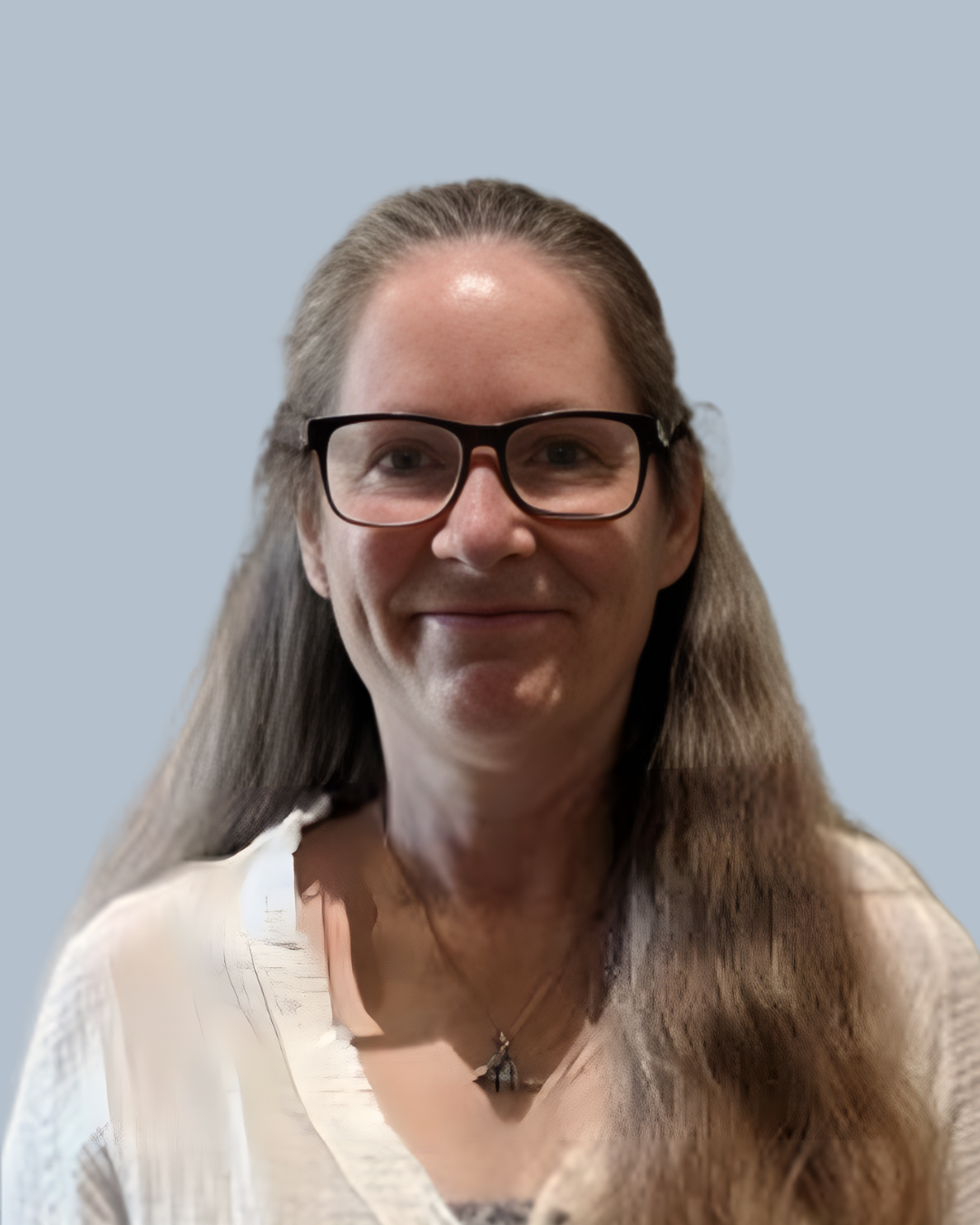 A woman with long brown hair, glasses, and a white top smiling at the camera against a light blue background.